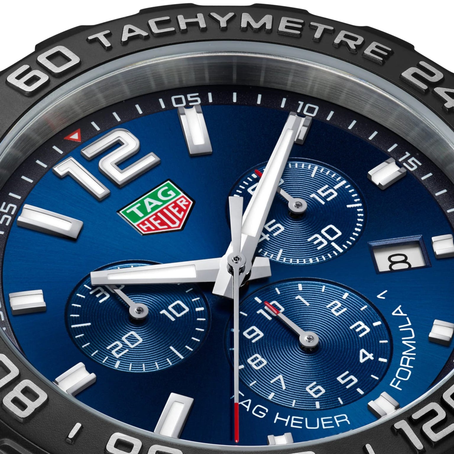 Close-up of a TAG Heuer Formula 1 Chronograph watch face with blue background, three subdials, date window, tachymeter bezel, and silver hands displaying the time at about 1:58:46.