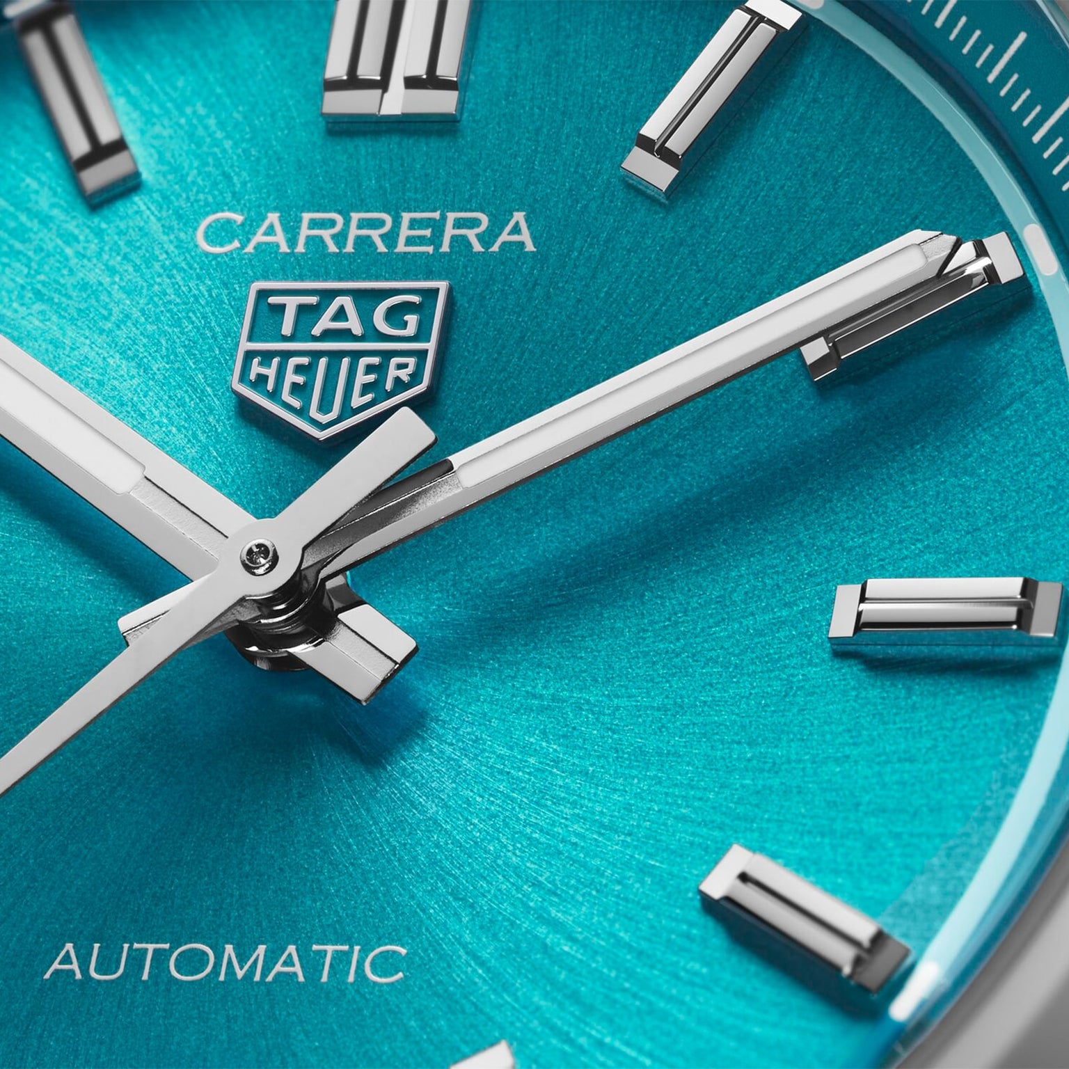 Close-up of a TAG Heuer Carrera Date watch face with silver hands and hour markers on turquoise, featuring CARRERA and AUTOMATIC labels—reflecting the spirited legacy of the Panamericana race.