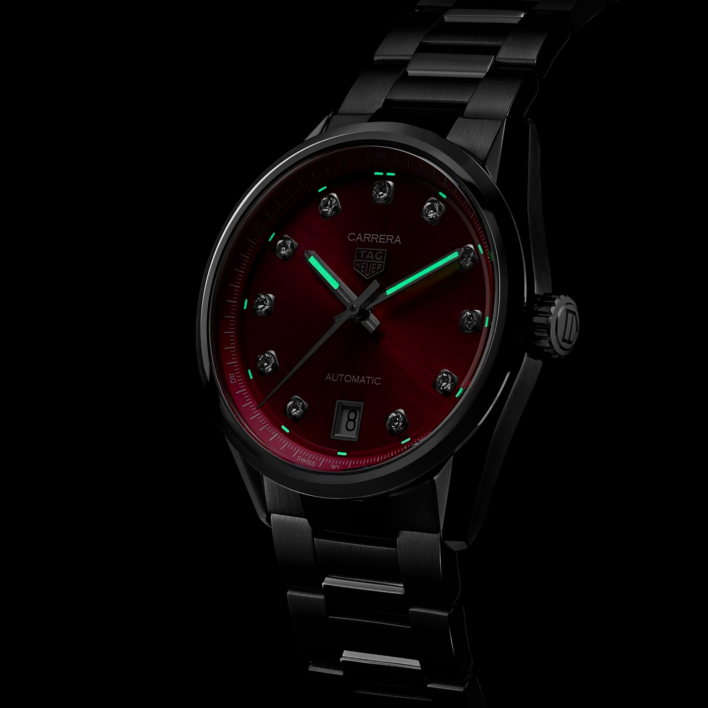 The TAG Heuer Carrera Date is a black metal automatic watch with a pink snail-brushed dial, luminous hands, VS diamond hour markers, and a date display at six o’clock, shown on a dark background.
