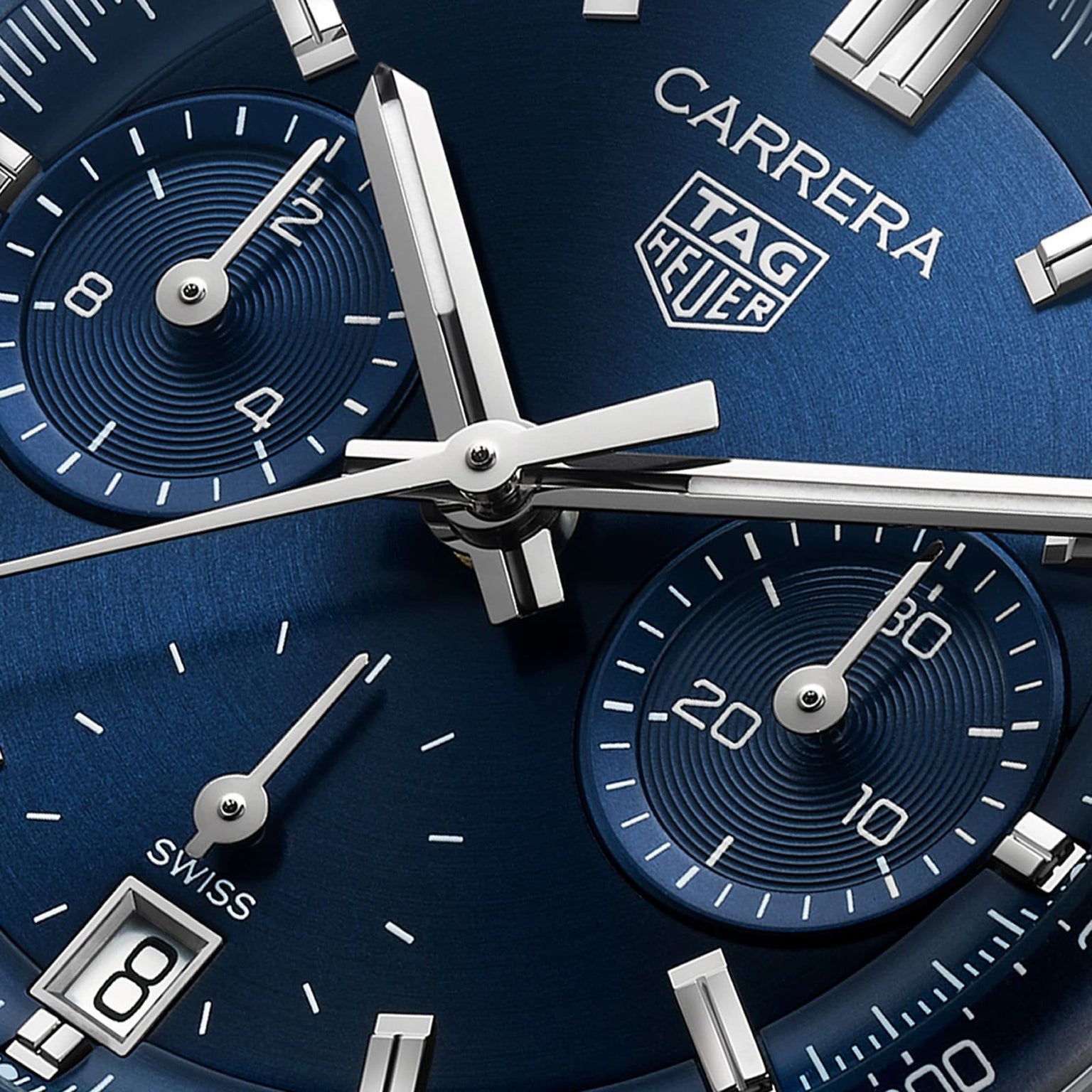 Close-up of a TAG Heuer Carrera Chronograph watch face in blue, featuring silver hands, subdials, and a date display.