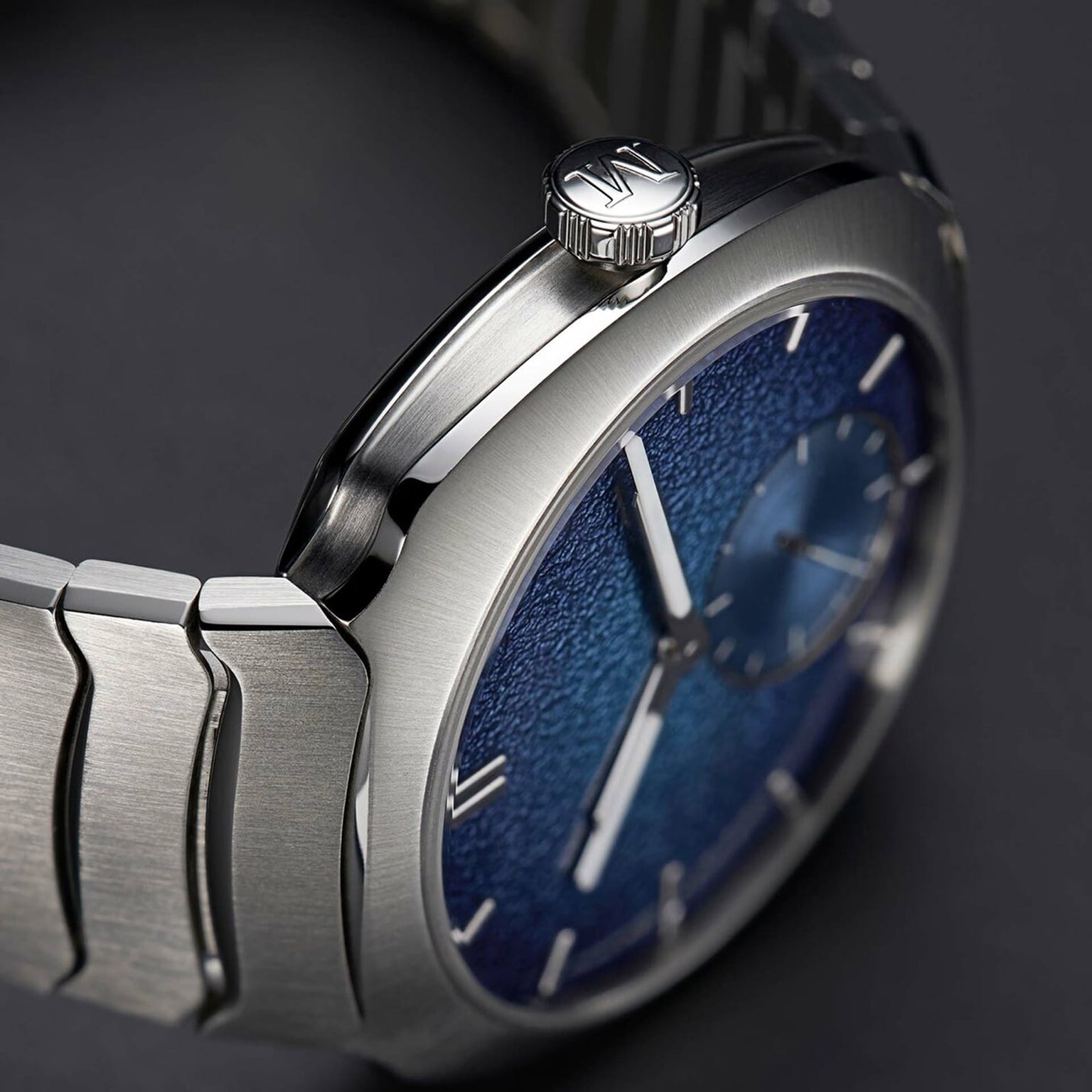 Close-up of the H. Moser & Cie Streamliner Small Seconds Blue Enamel, featuring a textured blue dial and brushed metal strap, set against a dark background.