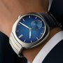 The H. Moser & Cie Streamliner Small Seconds Blue Enamel, featuring a textured blue face, is worn on a person’s wrist with a suit.
