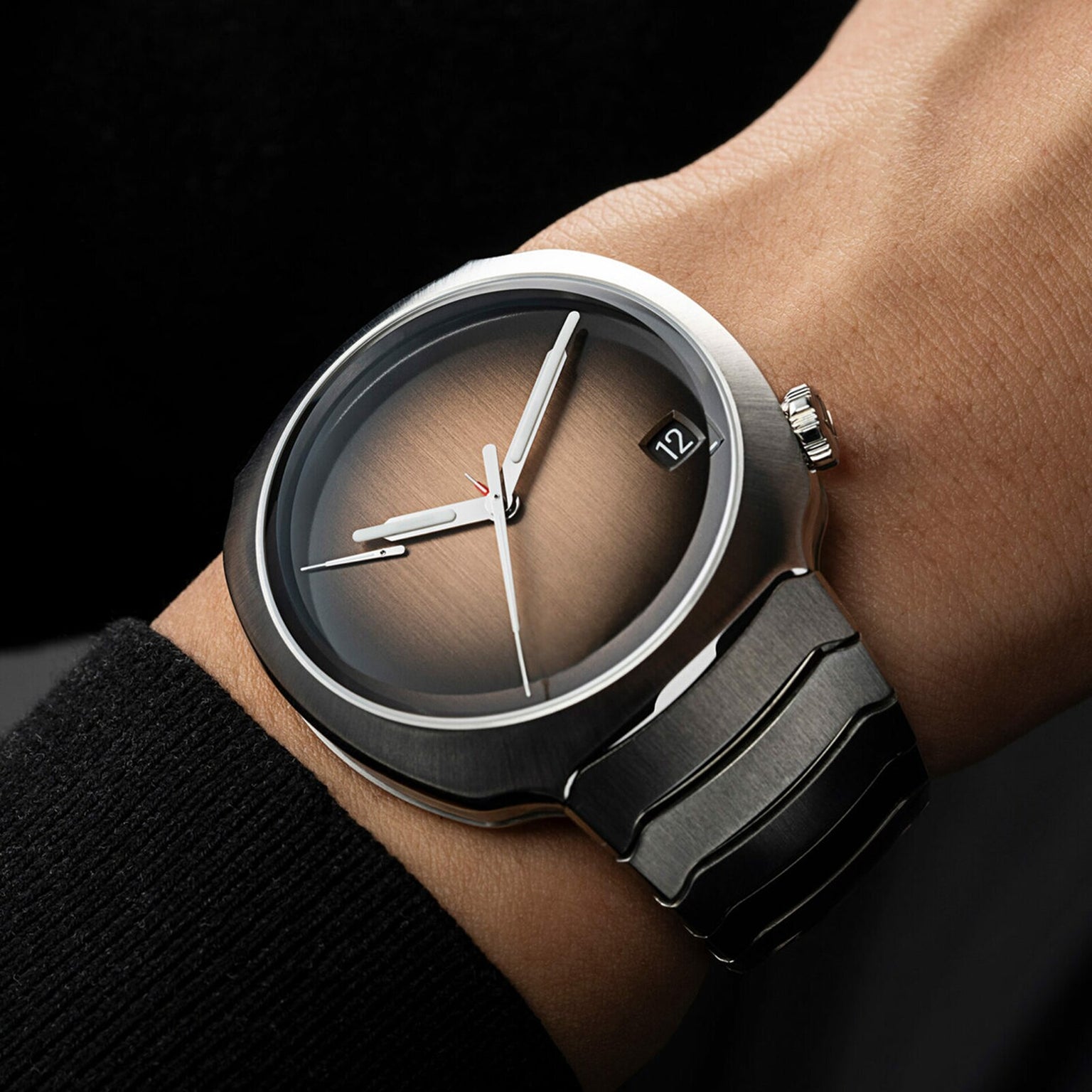 The H. Moser & Cie Streamliner Perpetual Calendar, featuring a brown gradient dial and black strap, is shown on a person’s wrist.