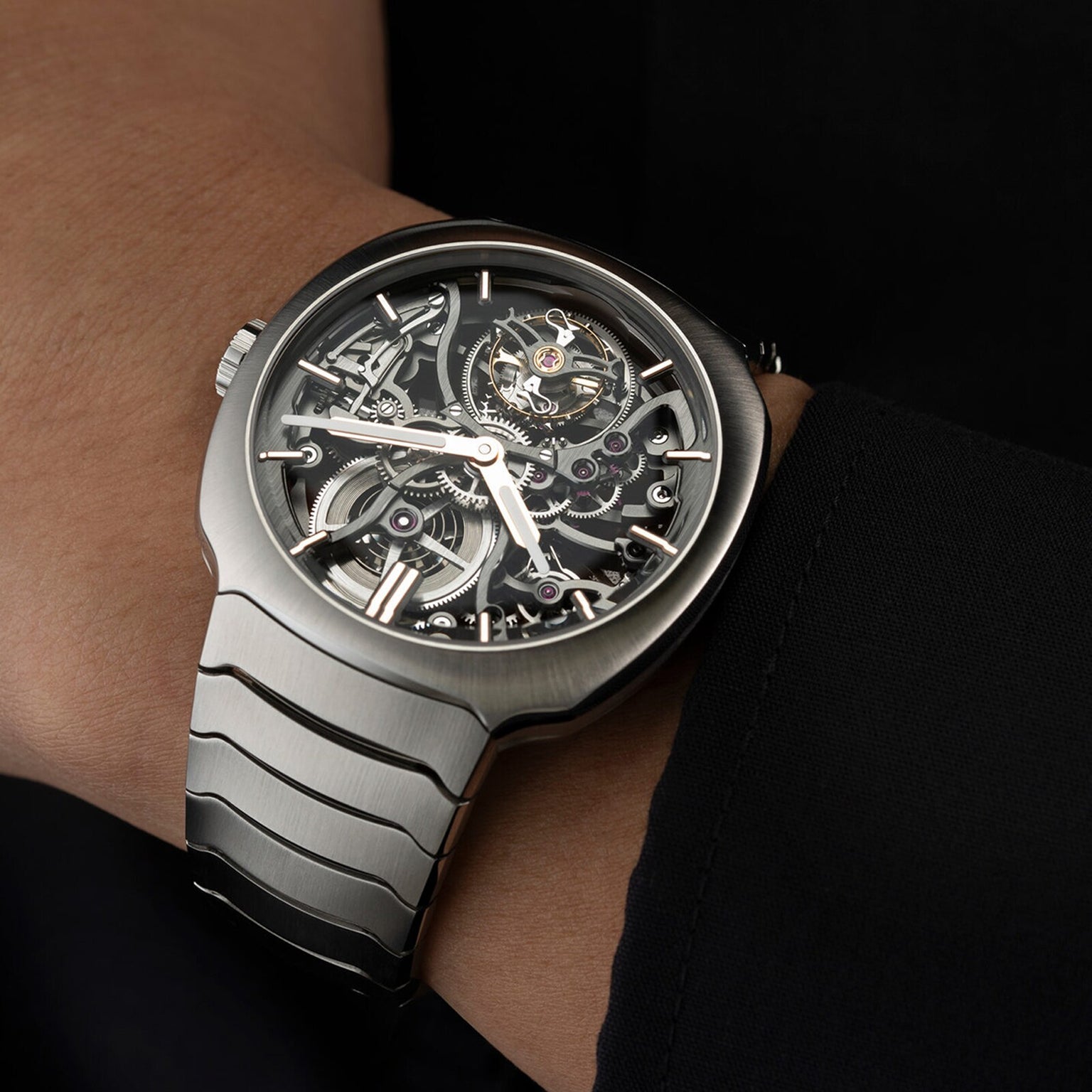 A close-up of the H. Moser & Cie Streamliner Tourbillon Skeleton watch, its visible movement displayed on a left wrist with a black sleeve, capturing minimalist style.