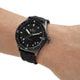 A person wearing a Blancpain Fifty Fathoms Bathyscaphe with a ceramic case, black dial, white markers, and a black fabric strap.