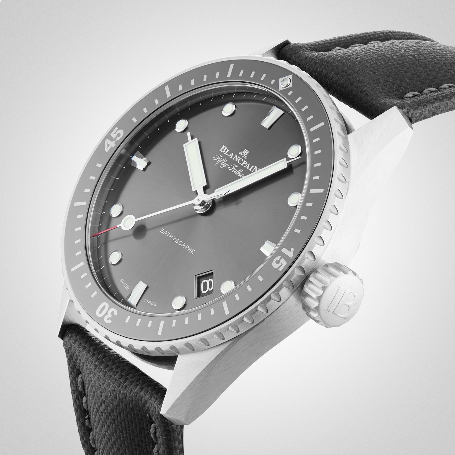 A close-up of a Blancpain Fifty Fathoms Bathyscaphe diver’s watch with a black dial, luminous markers, rotating bezel, automatic movement, and a black textured strap.