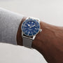 A person wears a Breitling Superocean Heritage B20 Automatic 42 with a silver mesh strap, gun blue ceramic bezel, stainless steel case, blue dial displaying 10:09, and a date window at 6 o’clock.