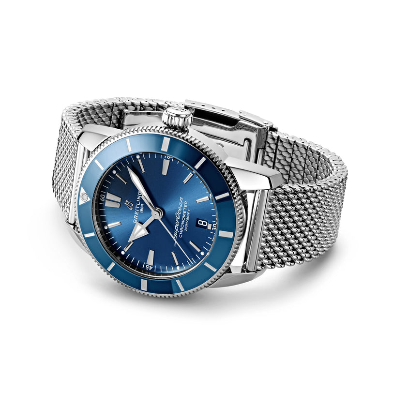 The Breitling Superocean Heritage B20 Automatic 44 features a silver stainless steel case, blue dial with silver hour markers, date display at 3 oclock, and metal mesh band; shown on a white background.