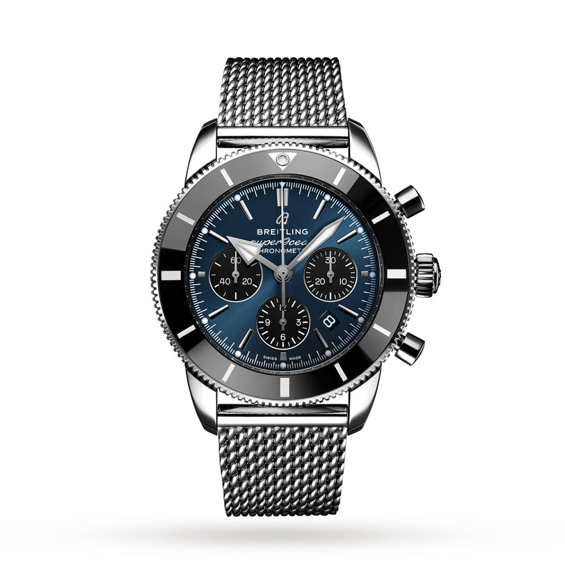 The Breitling Superocean Heritage B01 Chronograph 44 is a stainless steel diver’s watch with a blue dial, black bezel, three subdials, mesh bracelet, and Breitling 01 calibre, shown on a white background.