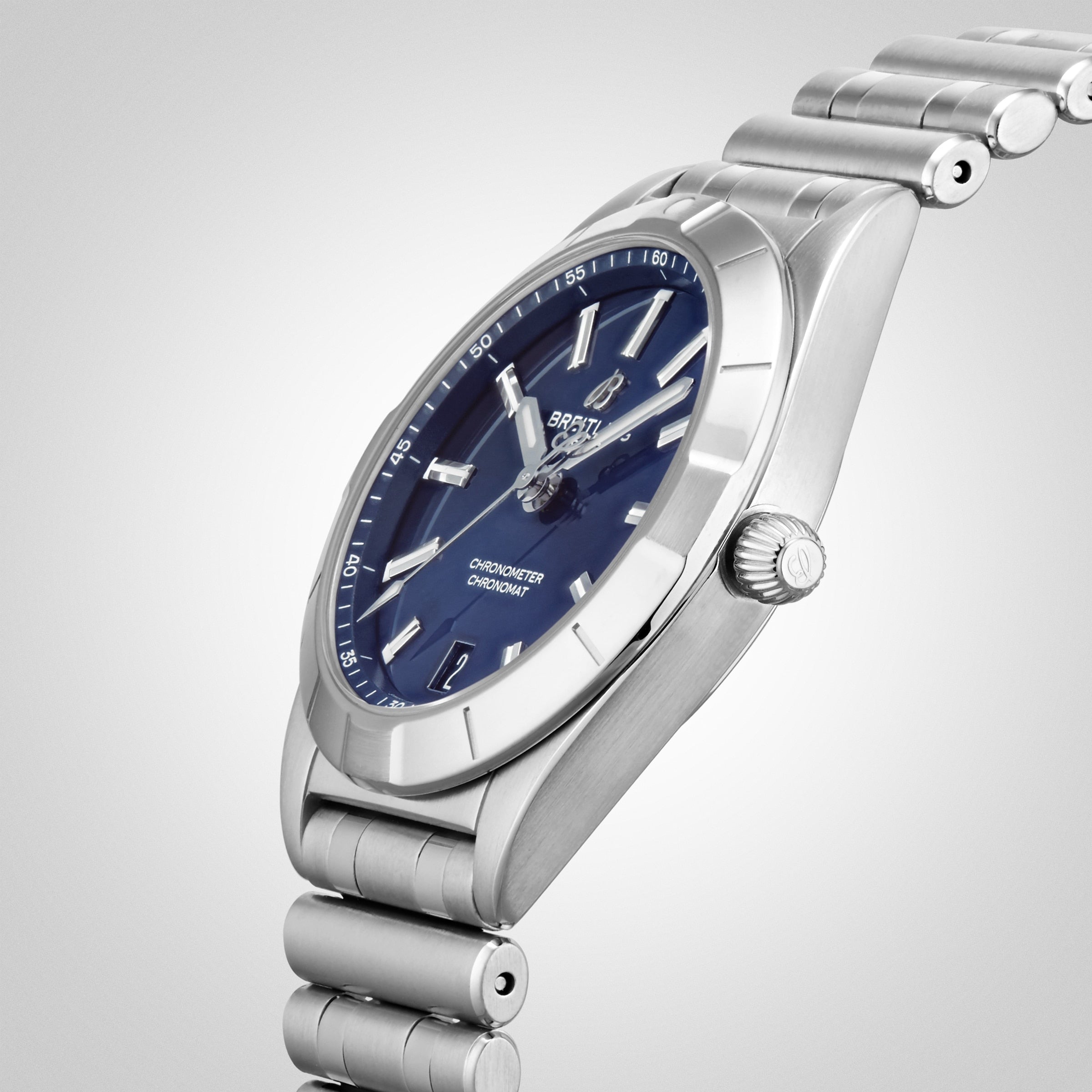 A Breitling Chronomat 32 COSC-certified stainless steel wristwatch with a blue dial, silver markers, and metal bracelet is displayed at an angle against a gradient light background.
