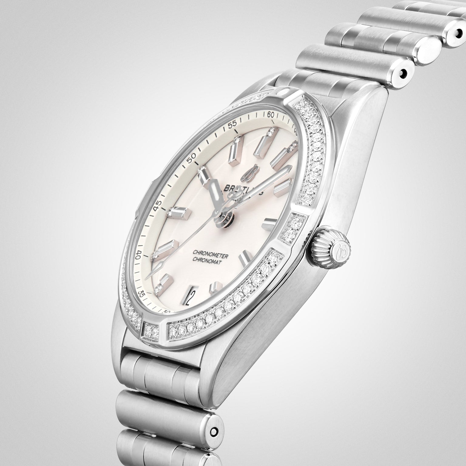 The Breitling Chronomat 32 is a silver wristwatch with a Rouleaux bracelet, diamond-accented bezel, and a light dial featuring silver hour markers and hands.