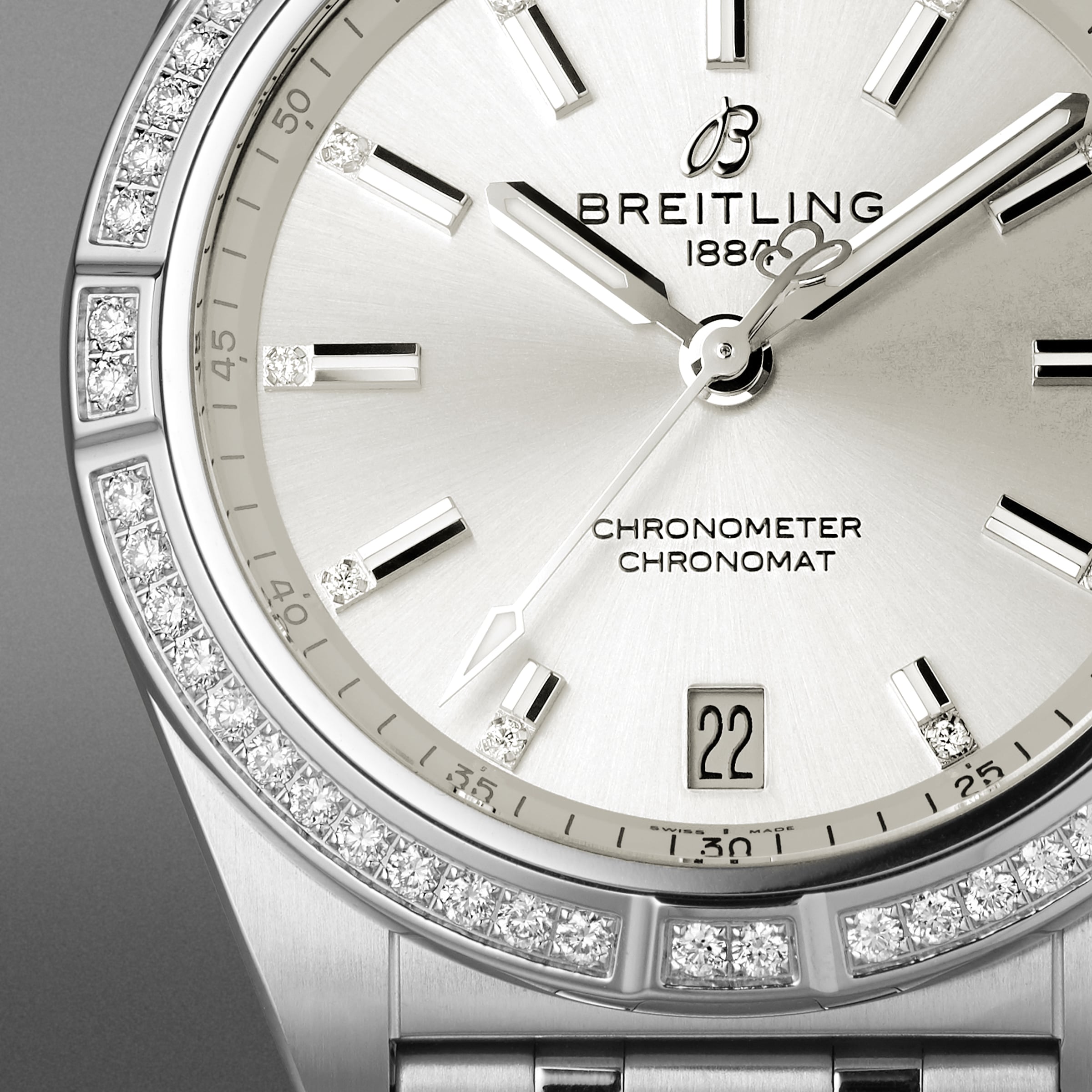 Close-up of the Breitling Chronomat 32 wristwatch featuring a silver dial, diamond hour markers, diamond-set bezel, date window at 6 o’clock, CHRONOMETER marking, and the signature Rouleaux bracelet.
