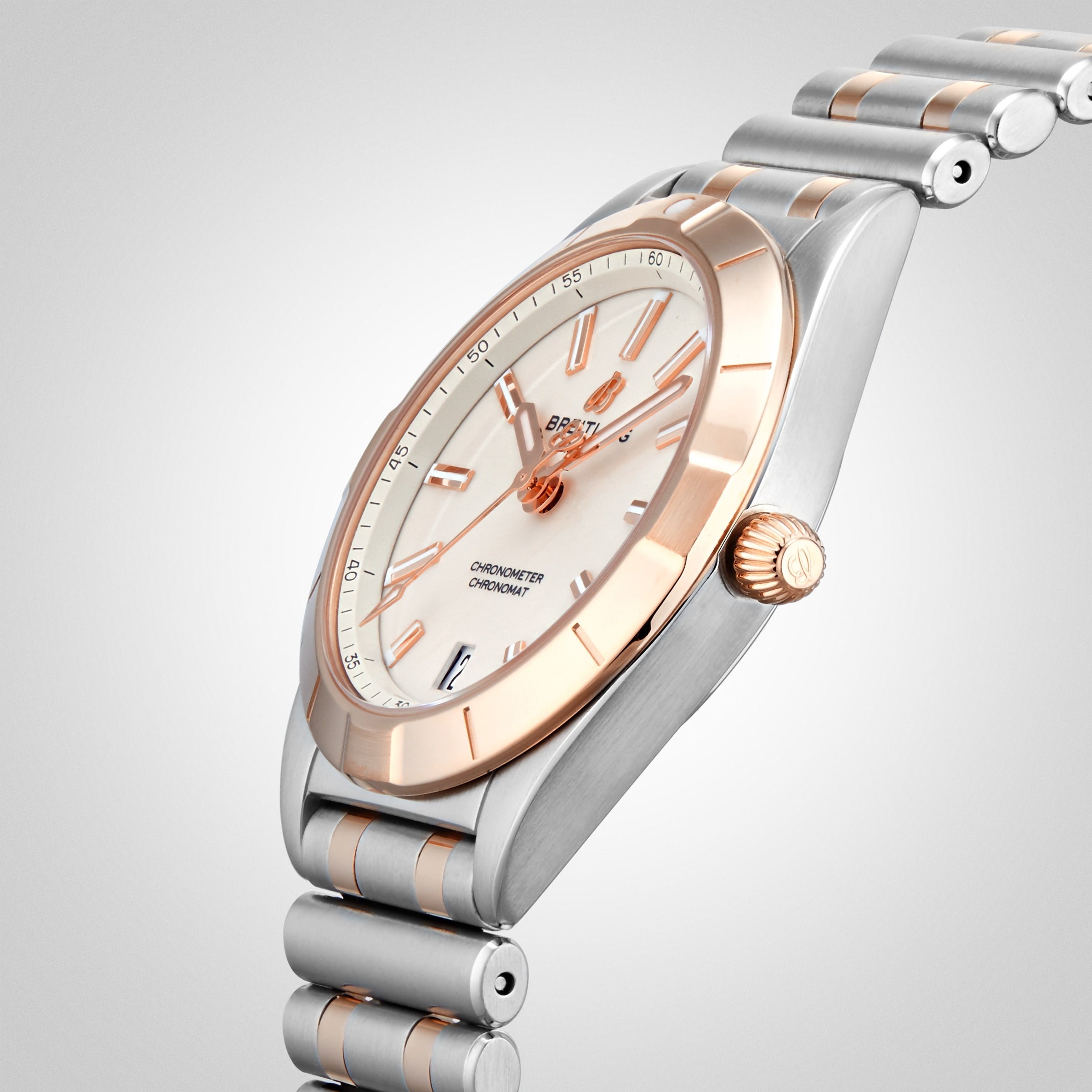 The Breitling Chronomat 32 is a luxury wristwatch with a silver and rose gold band, white dial, rose gold hands and markers, fluted crown, and is COSC-certified for accuracy. Photographed on a light gray background.