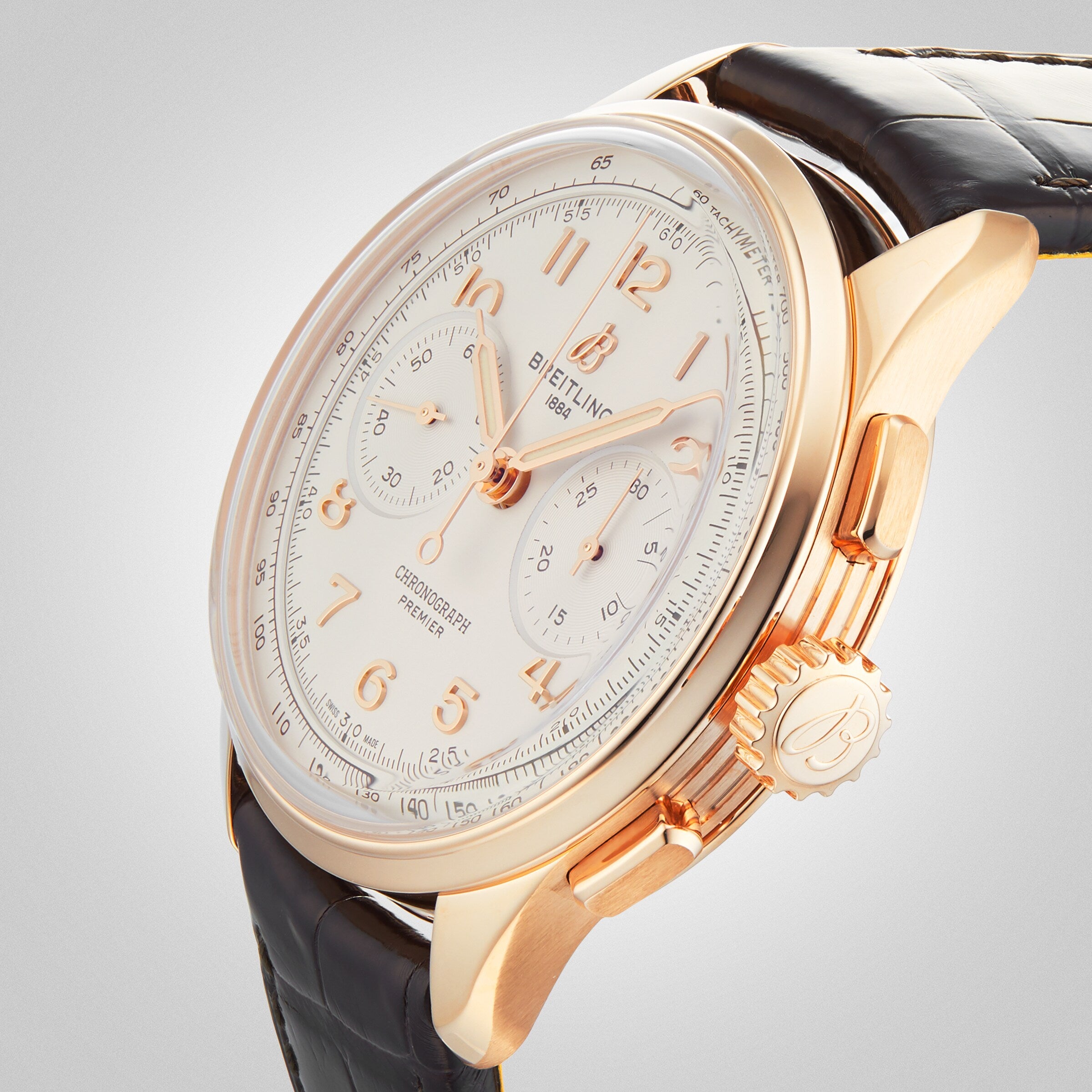 The Breitling Premier B09 Chronograph 40 features a 40mm 18K red gold case, white dial with three subdials, black leather strap, and side pushers, displayed against a plain background.