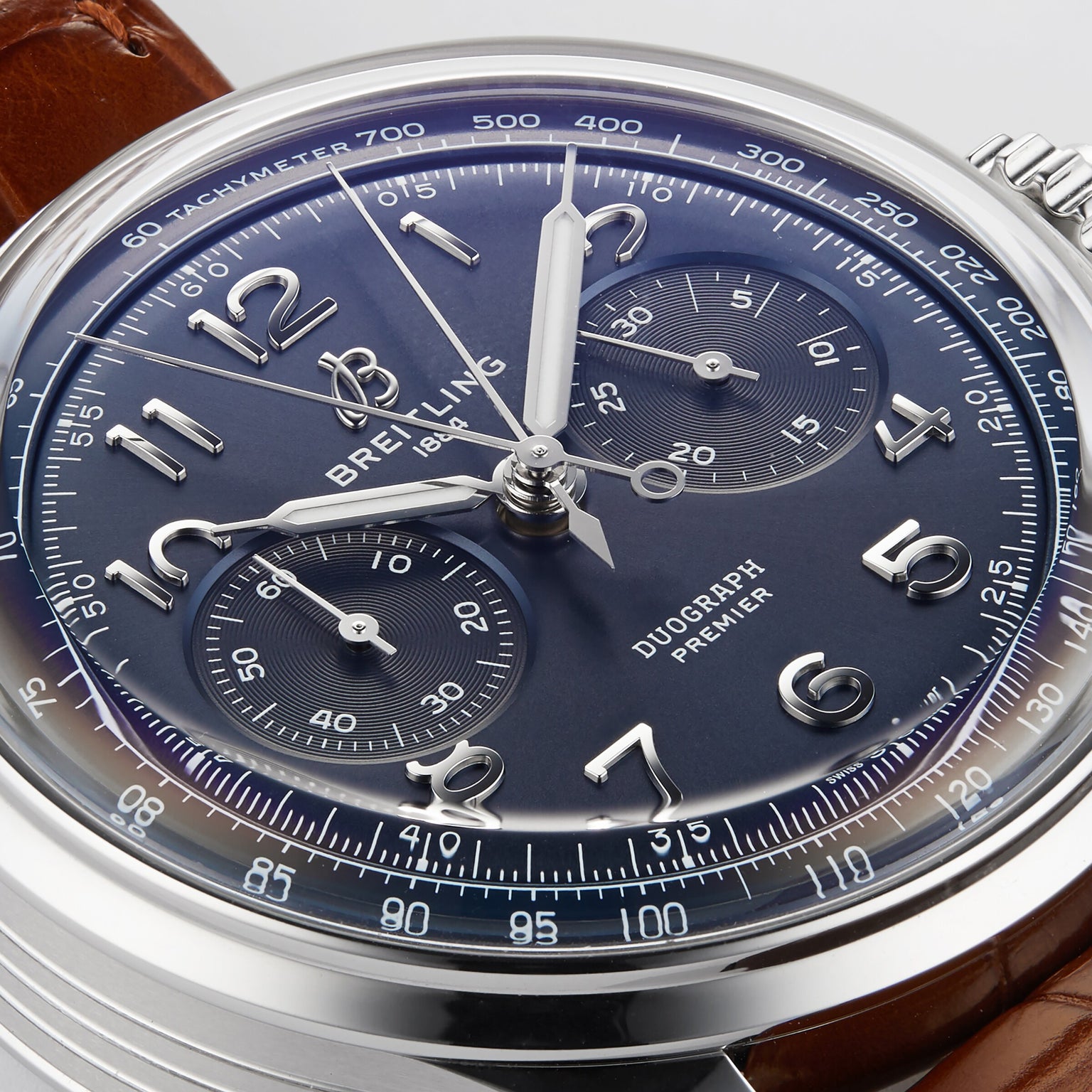 Close-up of the Breitling Premier B15 Duograph 42 with a blue dial, silver indices, chronograph subdials, brown leather strap, and COSC-certified chronometer movement.