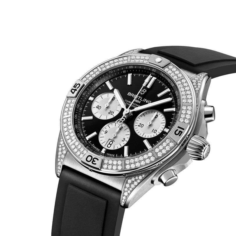 A luxury Breitling Chronomat B01 42 chronograph features a black dial with three subdials, diamond-encrusted bezel, black rubber strap, and COSC-certified chronometer movement, photographed on a white background.