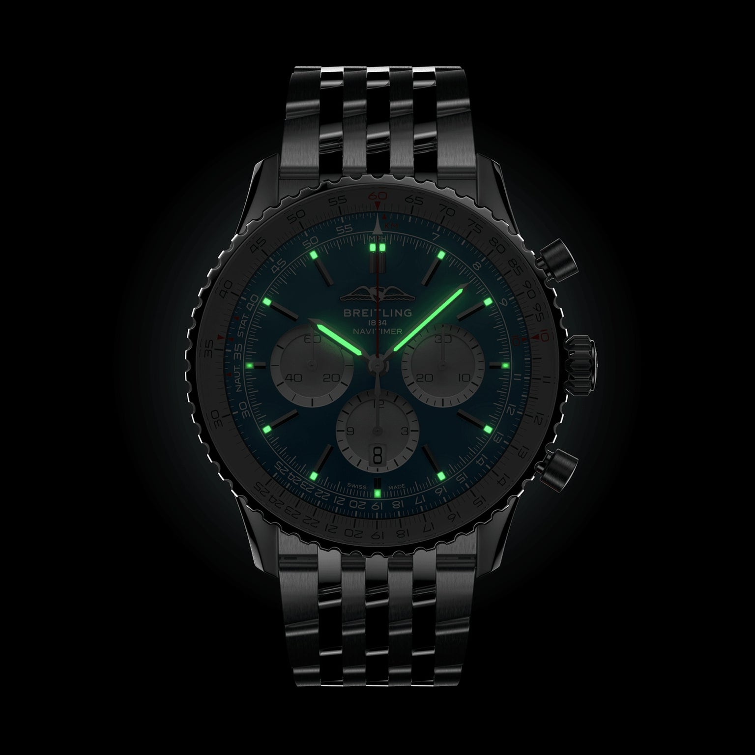 A Breitling Navitimer B01 Chronograph 46 wristwatch with a black dial and metal bracelet is shown in the dark, featuring glowing green luminescent hands and hour markers.