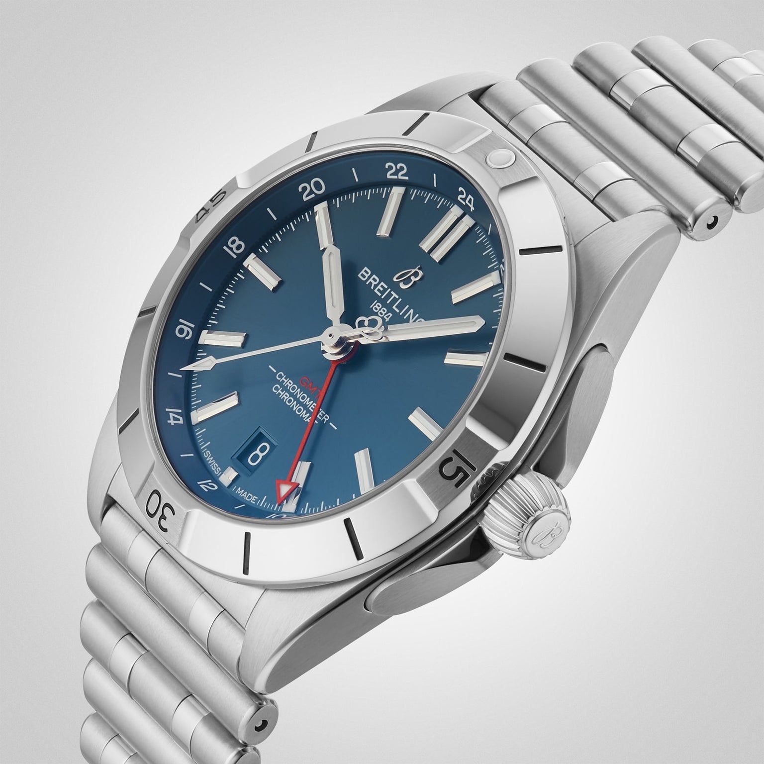 The Breitling Chronomat Automatic GMT 40 stainless steel watch features a blue dial, silver hour markers, a date window at 6 o’clock, and a metal link bracelet, shown here from an angled perspective.