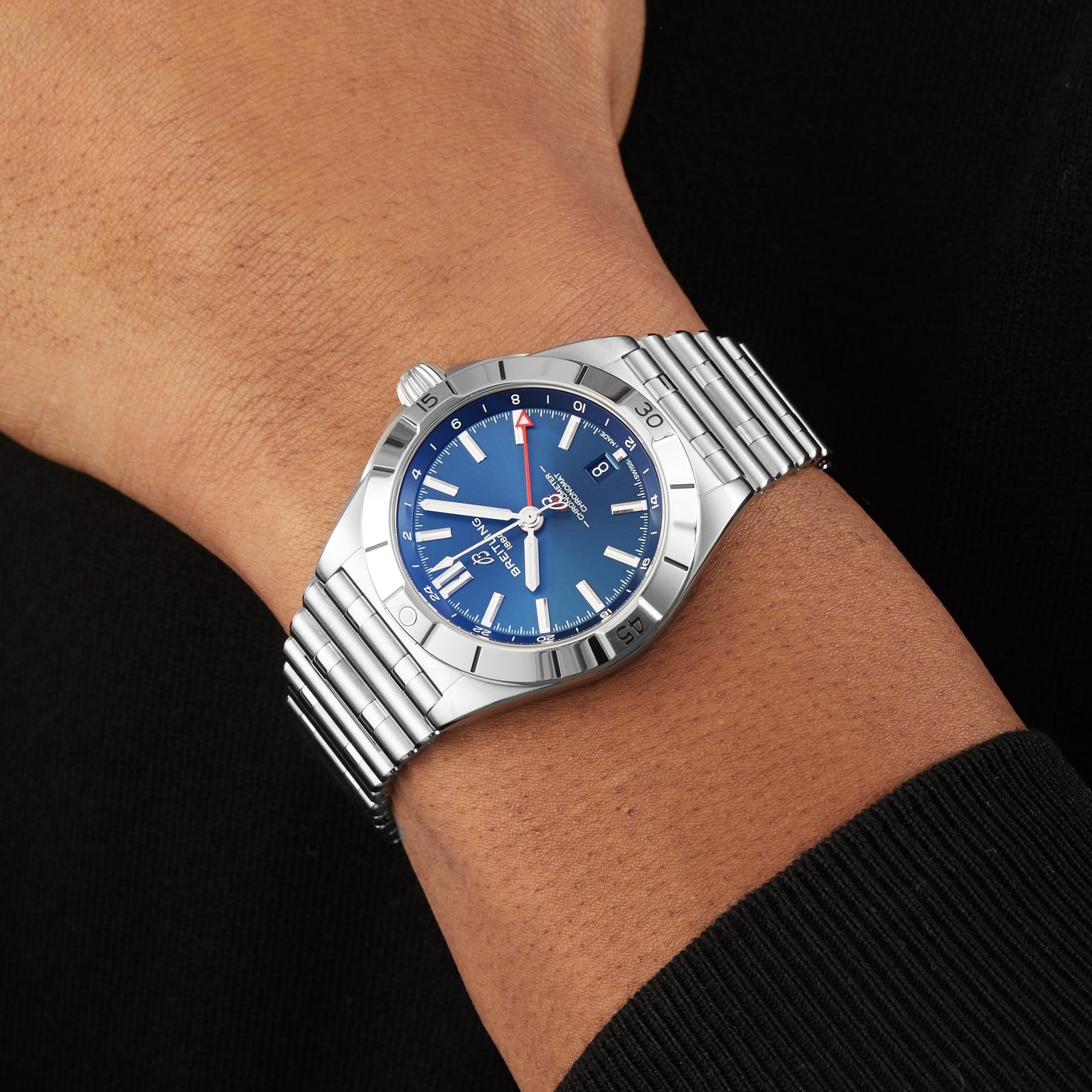 A Breitling Chronomat Automatic GMT 40 wristwatch with a blue dial and silver hour markers is worn on a persons left wrist.