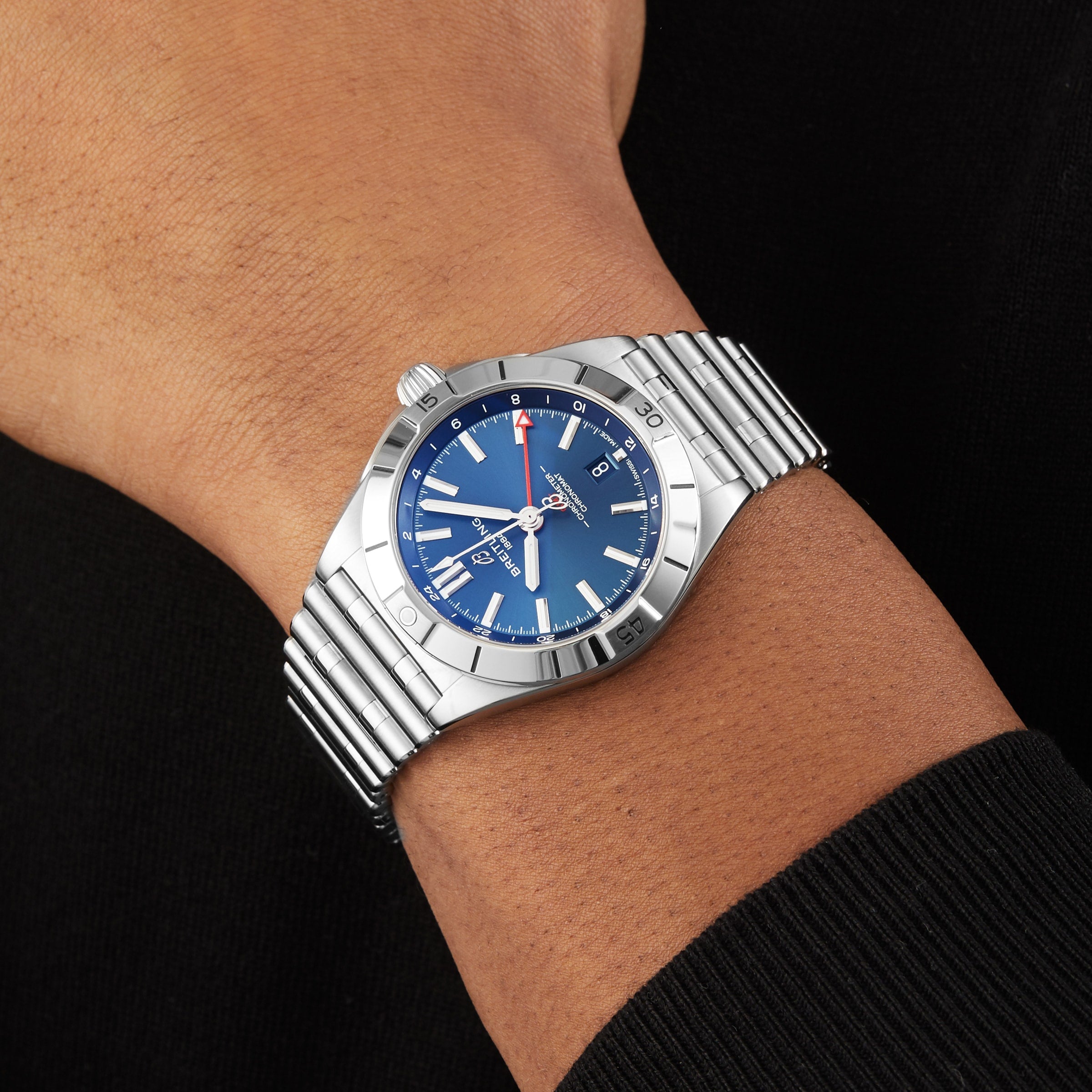 A Breitling Chronomat Automatic GMT 40 wristwatch with a blue dial and silver hour markers is worn on a persons left wrist.