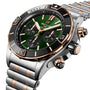 A close-up of the Breitling Super Chronomat B01 44, a luxury chronograph watch with an emerald dial, black bezel, and a silver and rose gold metal bracelet.