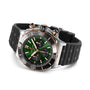 The Breitling Super Chronomat B01 44 is a stainless steel and gold chronograph with a green dial, black bezel, black textured rubber strap, two side pushers, and is powered by the Breitling 01 calibre.