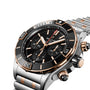 A close-up of the Breitling Super Chronomat B01 44 wristwatch, featuring a black dial, 18ct rose gold and silver accents, and a metal bracelet. COSC certified for precision.