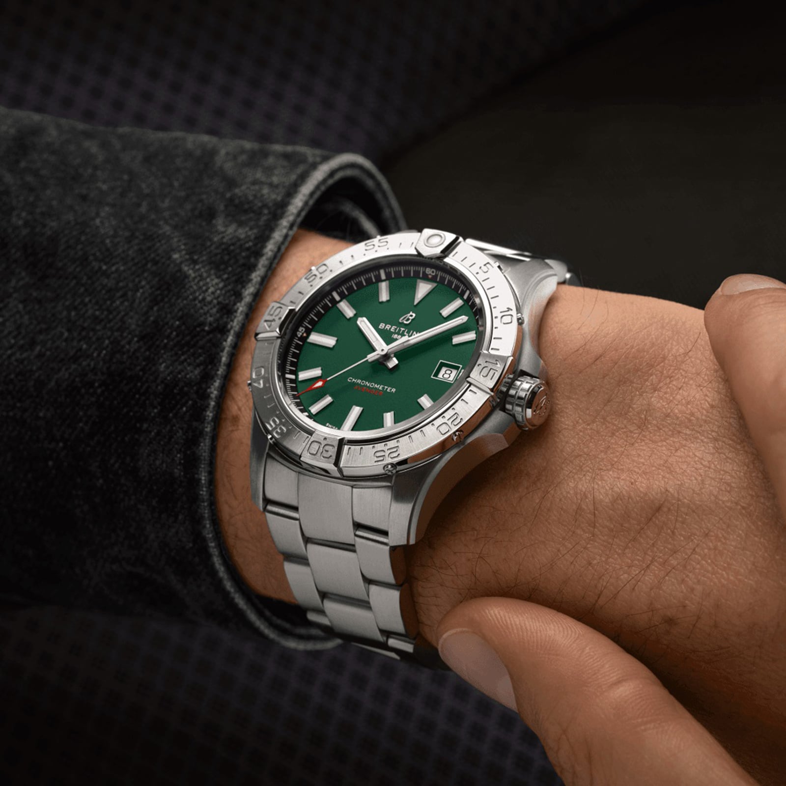 A person wearing a Breitling Avenger Automatic 42 with a military green dial and silver bezel on their left wrist.