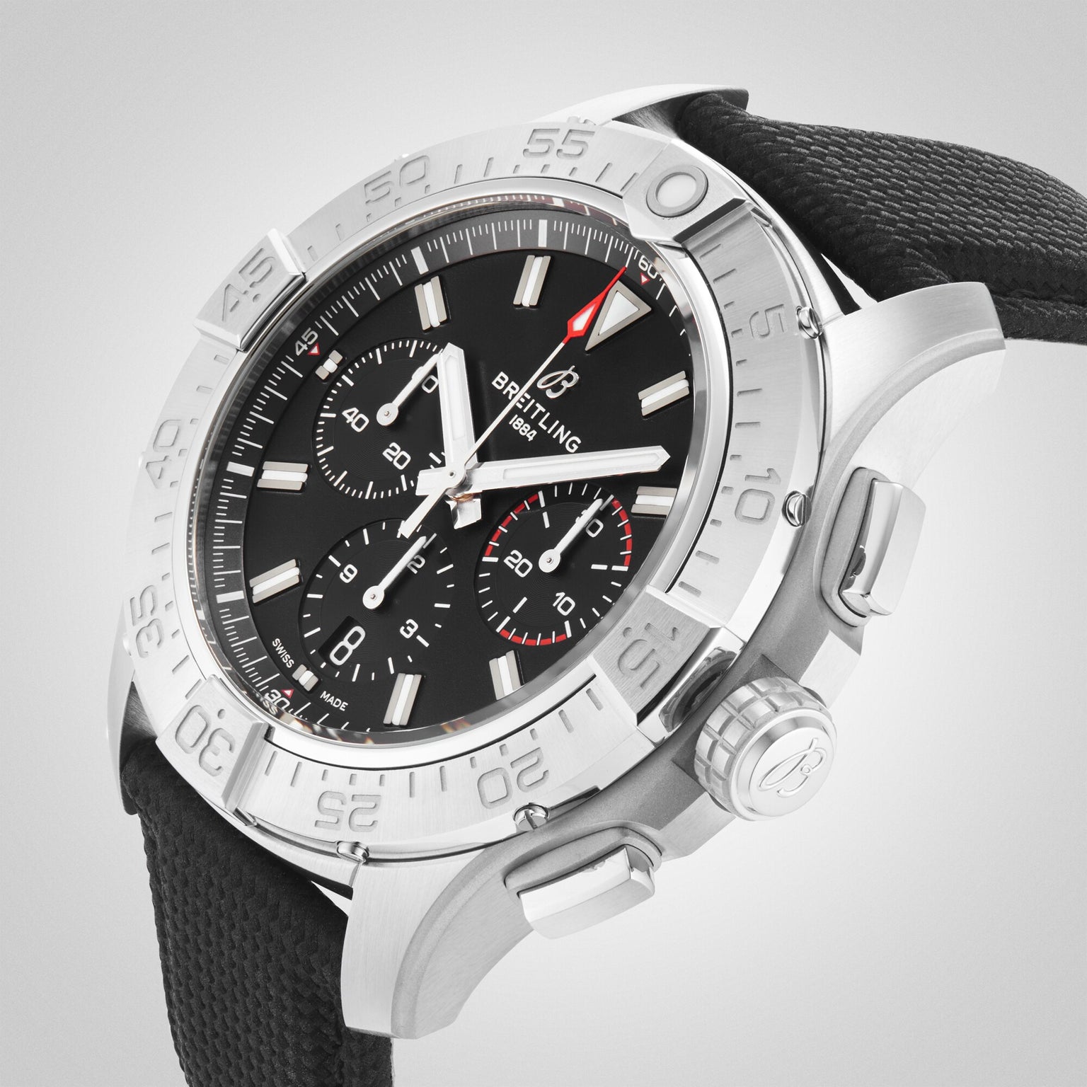 The Breitling Avenger B01 Chronograph 44, crafted in stainless steel with a black dial, three subdials, silver hour markers, and a black fabric strap, exudes rugged military style in an angled photograph.