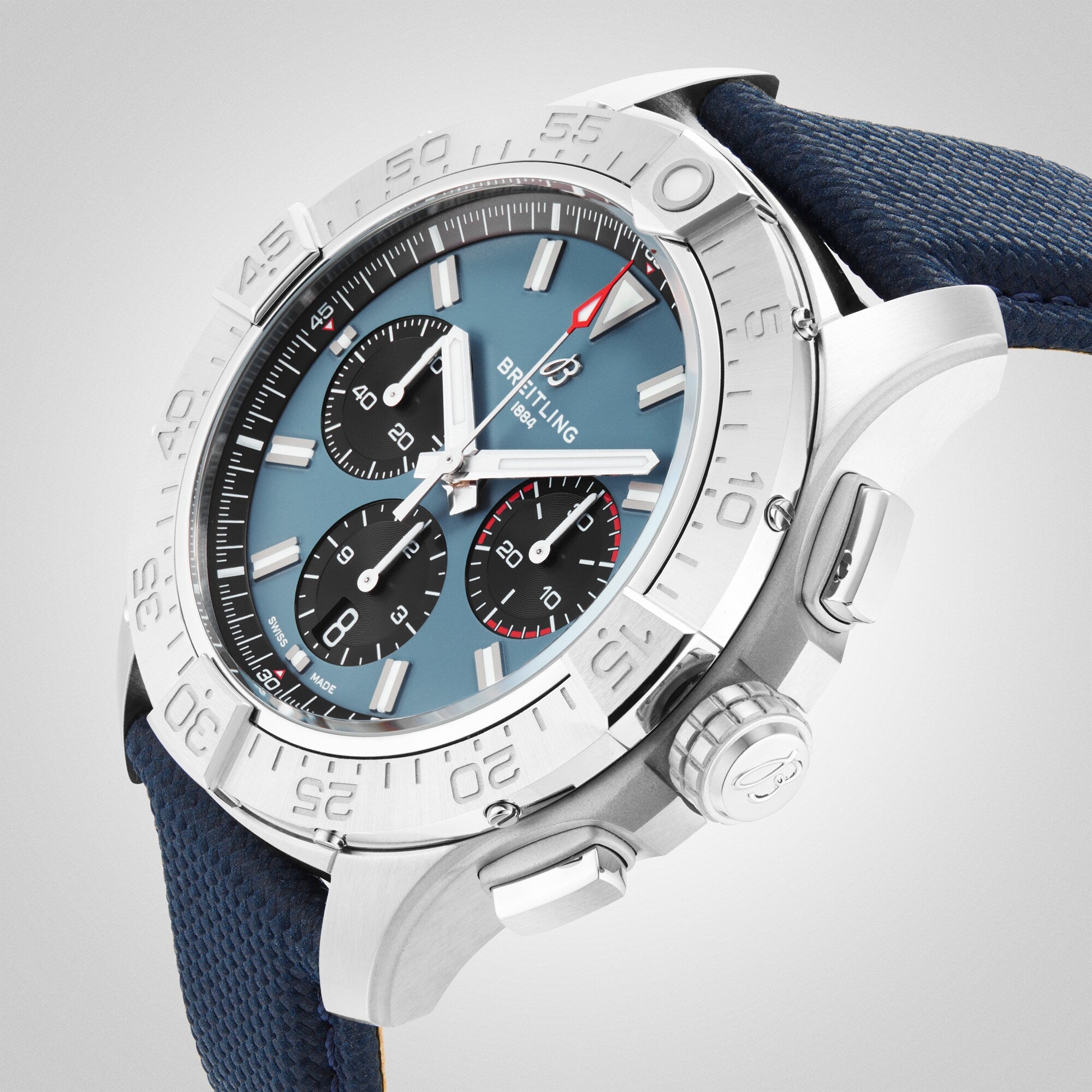 A close-up of the Breitling Avenger B01 Chronograph 44 wristwatch featuring a blue dial with three subdials, stainless steel case, blue fabric strap, and precise self-winding mechanical movement.