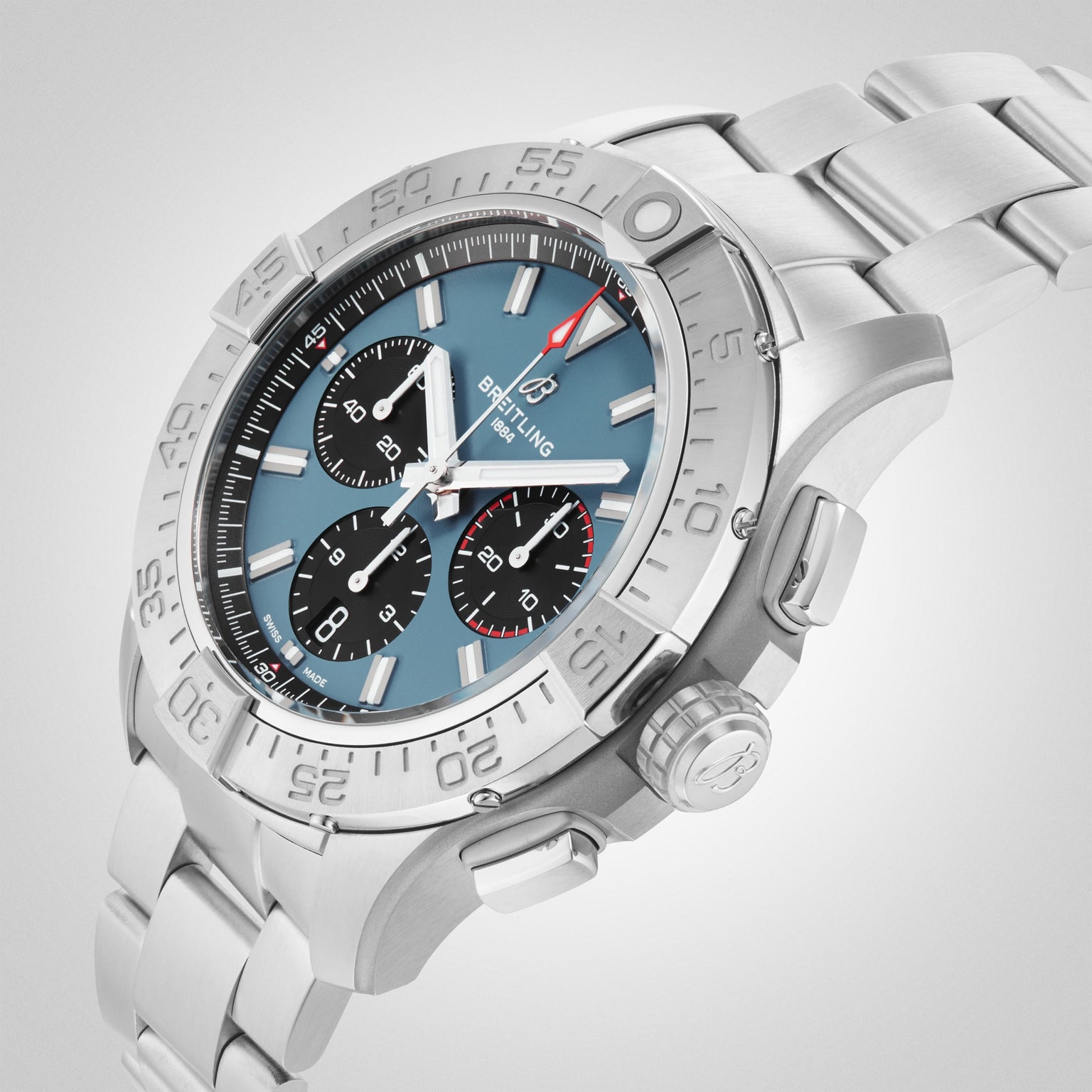 The Breitling Avenger B01 Chronograph 44 features a stainless steel case, blue dial with three black subdials, silver hour markers, and a metal bracelet—showcasing bold aviation design against a light background.