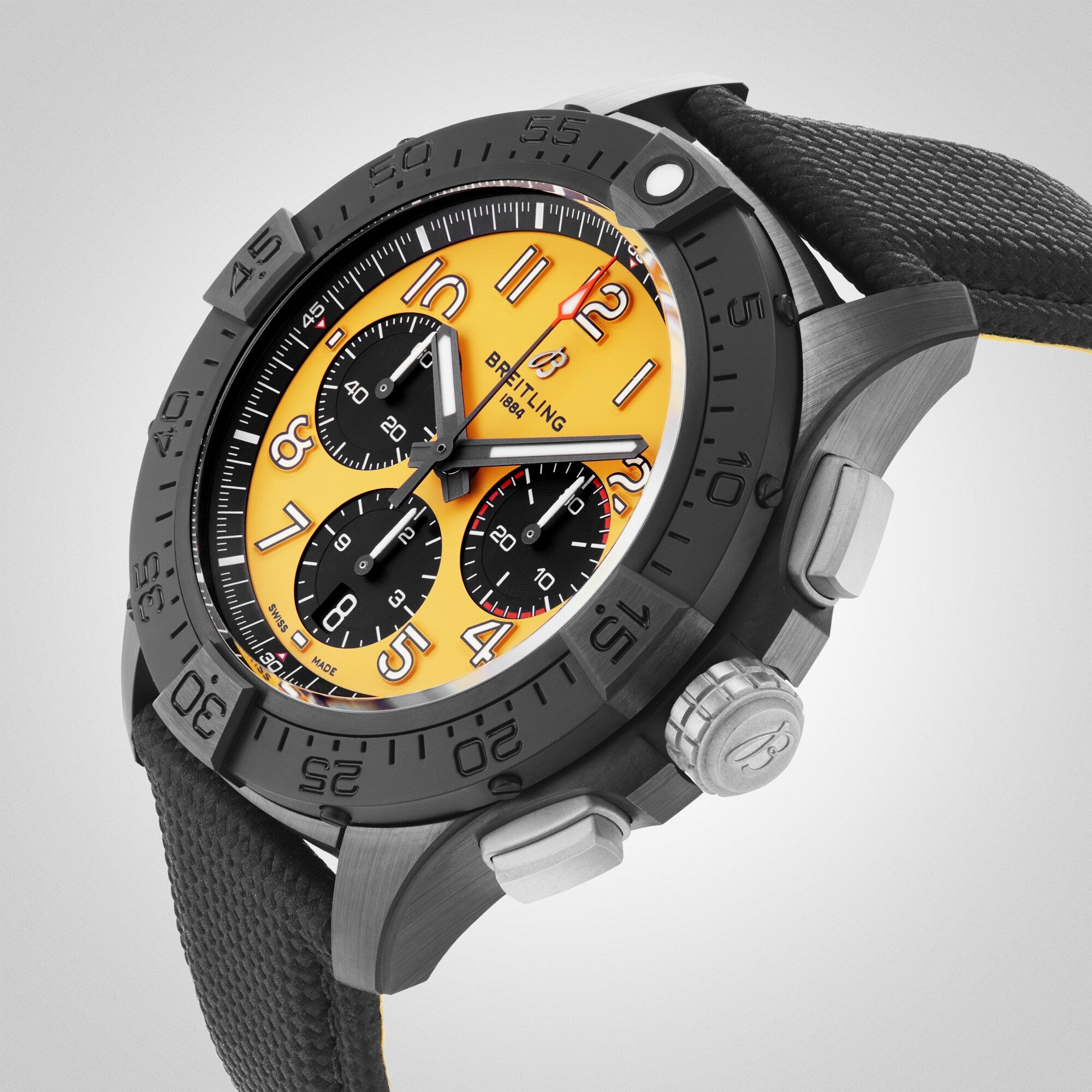 The Breitling Avenger B01 Chronograph 44 Night Mission wristwatch features a yellow dial, black bezel, three subdials, a black textured strap, and a ceramic-titanium case, displayed from an angled perspective.