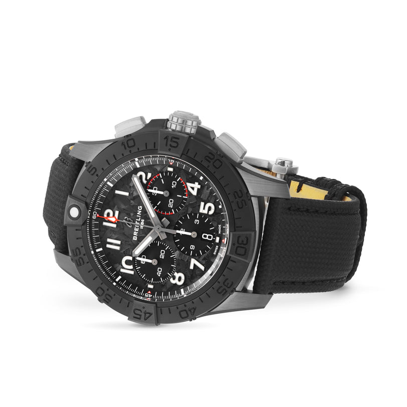 The Breitling Avenger B01 Chronograph 44 Night Mission features a black dial, bold bezel, and three subdials on a fabric strap, shown at an angle against a white background.