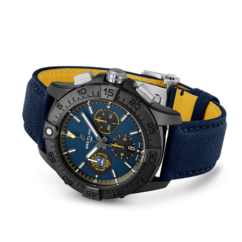 The Breitling Avenger B01 Chronograph 44 Night Mission US Naval Academy features a blue dial, black bezel, three subdials, and a blue textured military leather strap with yellow lining.