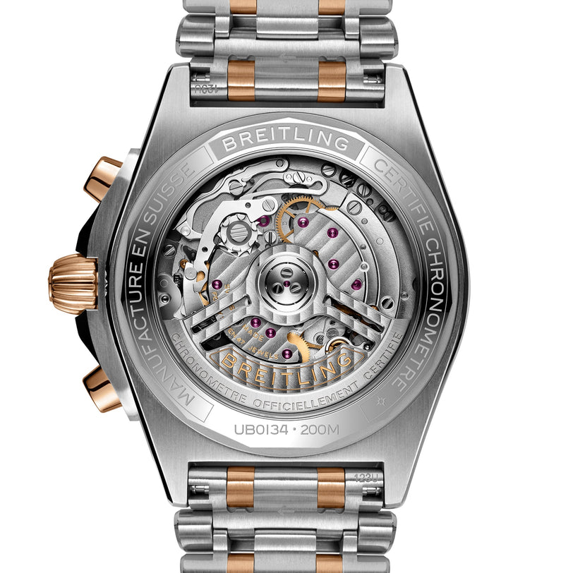 Close-up of the back of the Breitling Chronomat B01 42, revealing its exposed Breitling Manufacture 01 mechanical movement, COSC certified label, and a metal bracelet featuring silver and gold accents.