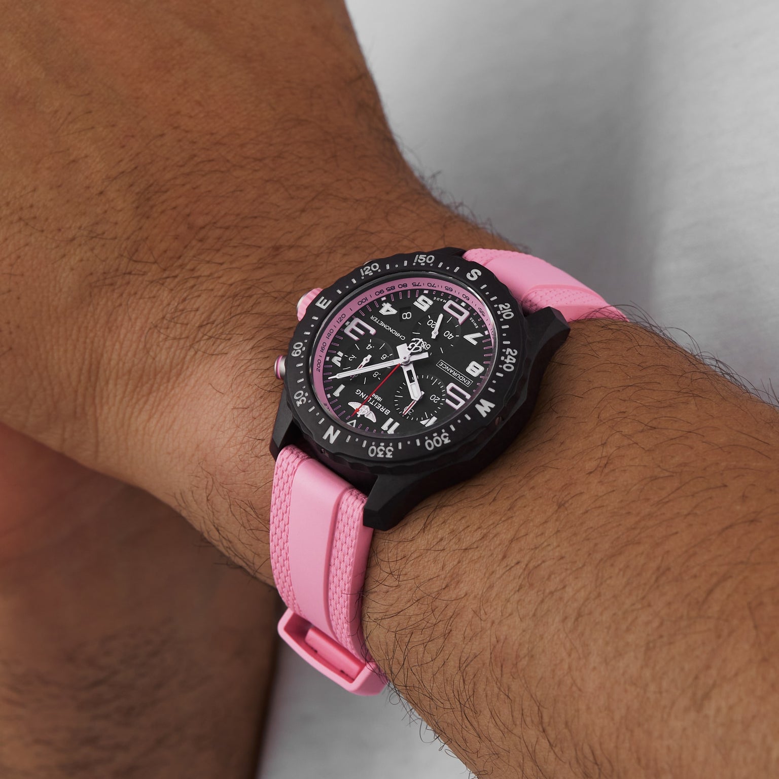The Breitling Endurance Pro 38 is a stylish athleisure watch with a black analog face, white markings, compass directions, pink band, and lightweight Breitlight case—ideal for everyday comfort and sport.