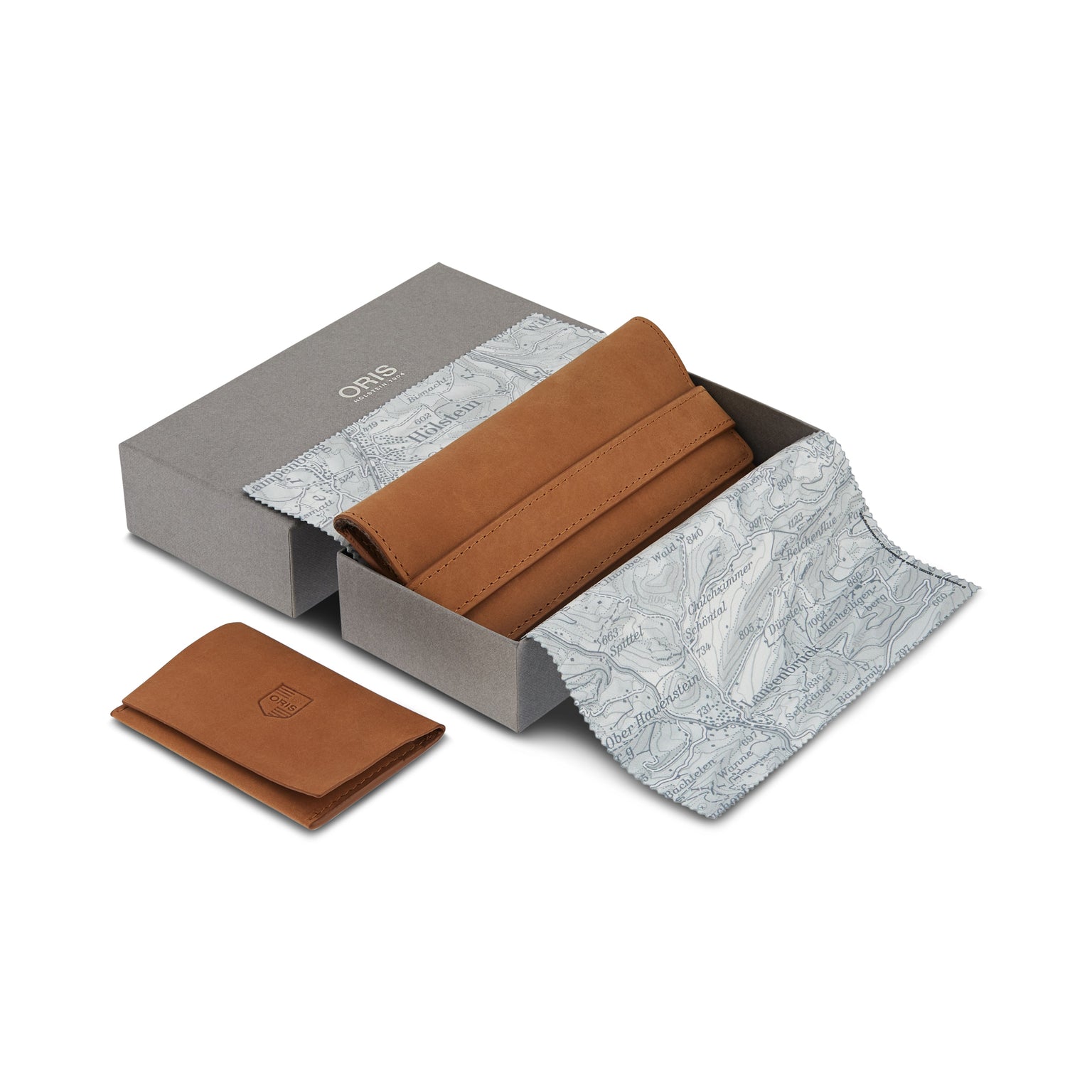 A brown leather watch roll, ideal for your Oris Big Crown Pointer Date 80th Anniversary Edition with green dial, is partially wrapped in patterned cloth in an open grey box, with a matching leather card holder included.