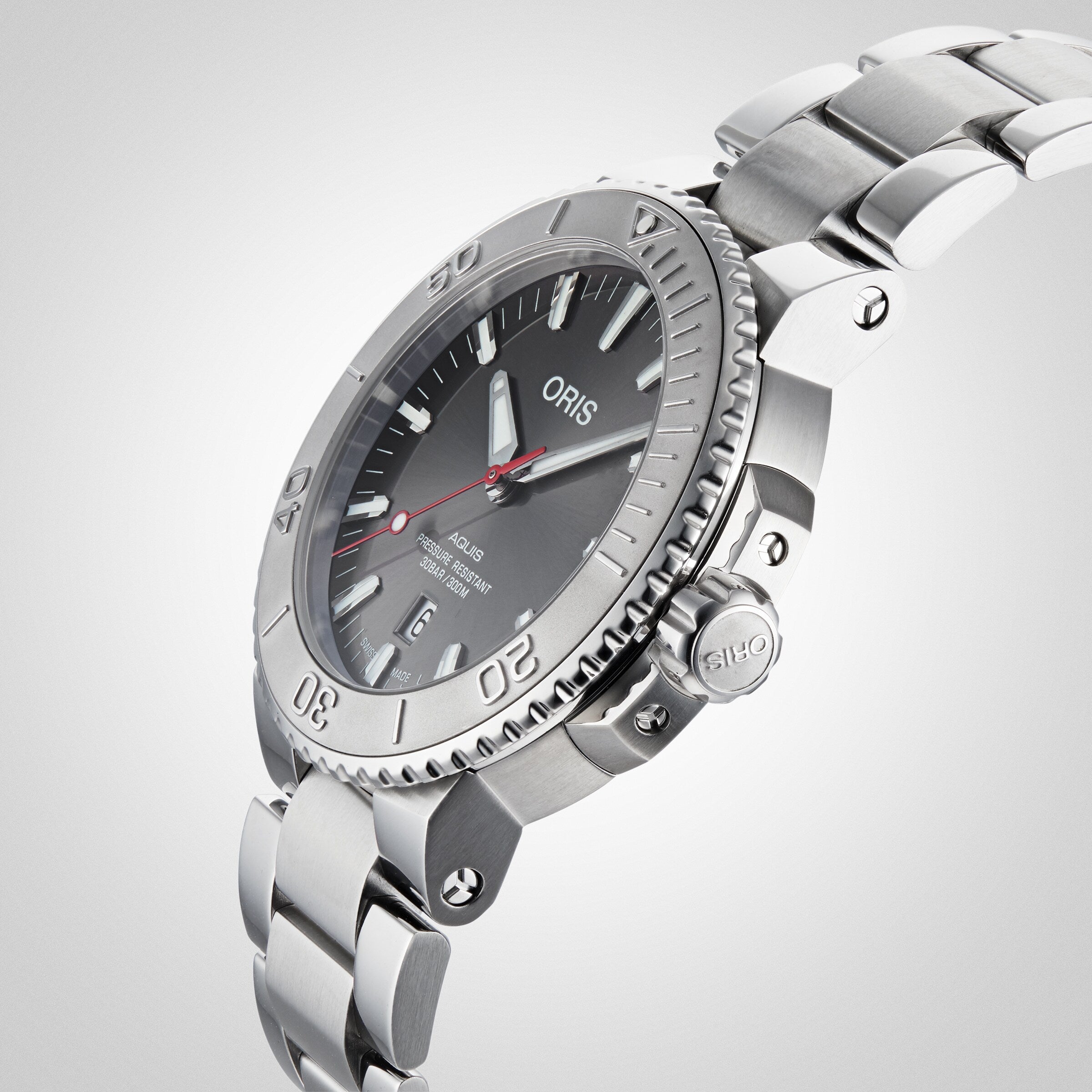 Oris Aquis Date Relief wristwatch with a metal band, black dial, and red seconds hand, displayed at an angle on a white background.