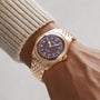 An Oris Big Crown Bronze Pointer Date wristwatch with a brown dial and metal band worn on a person’s wrist in a beige sweater.