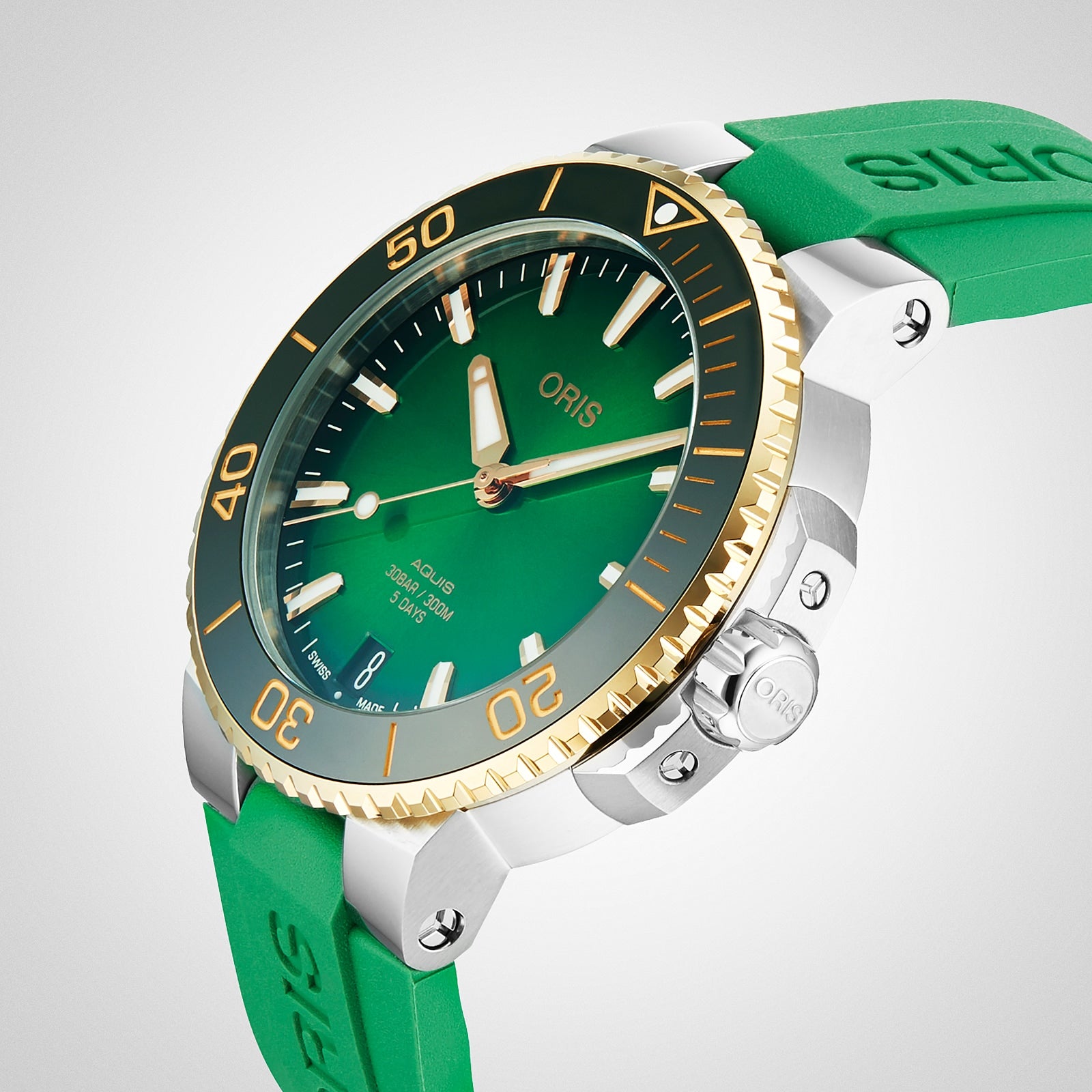 A close-up of the Oris Aquis Date Calibre 400, showcasing a green dial, gold and green bezel, and green rubber strap. This automatic watch features prominent hour markers, hands, date display, and is powered by the Calibre 400.