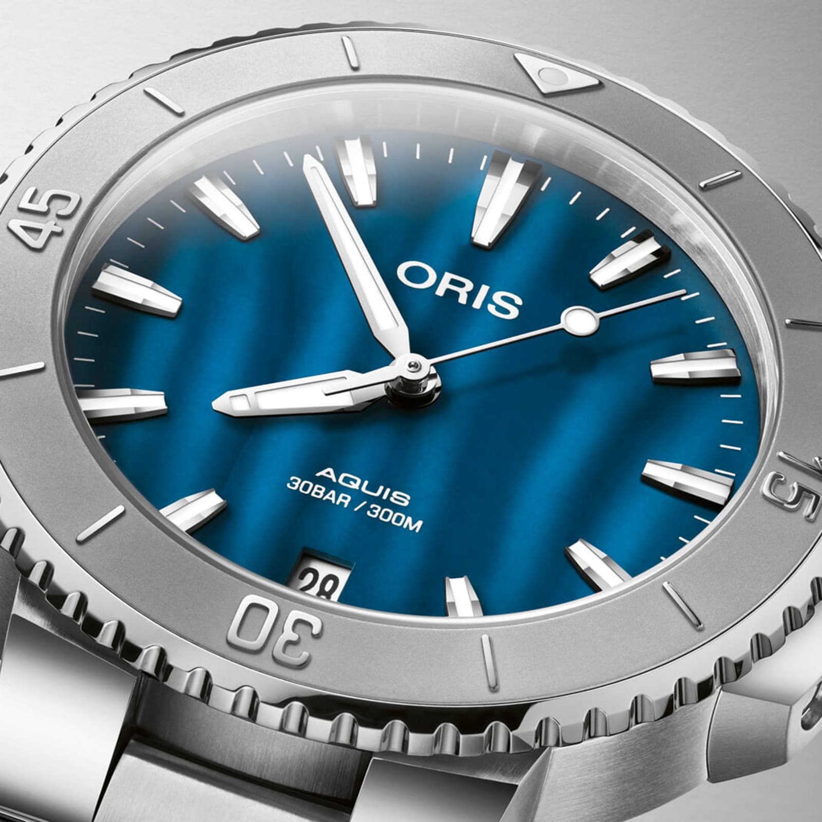 Close-up of the Oris Aquis Date, featuring a blue wave-patterned dial, silver hour markers, and a stainless steel bezel, displaying the time as 1:51:29.