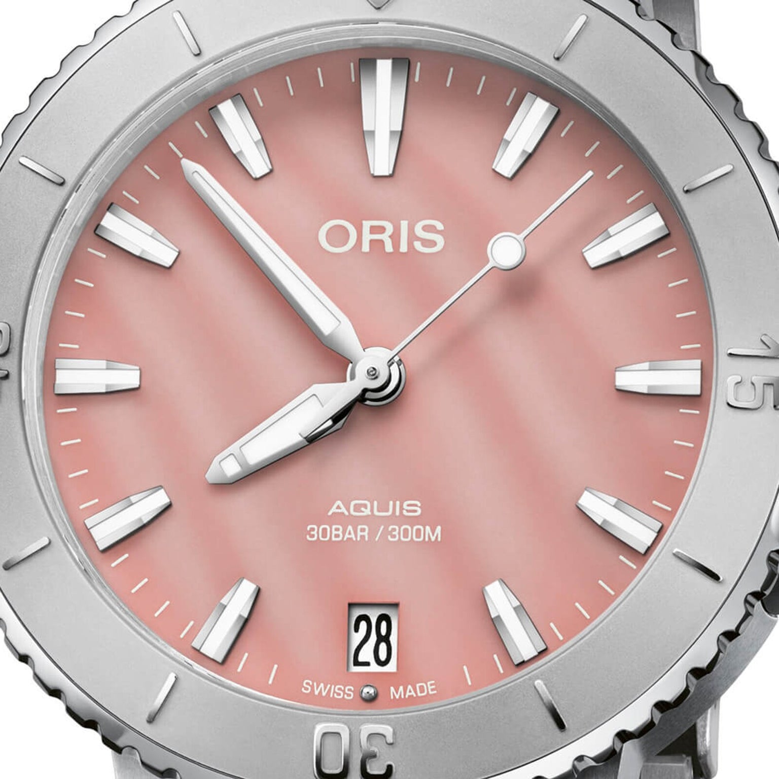 Close-up of the Oris Aquis Date watch, showcasing a blush pink dial with silver markers and hands, date display at 6 o’clock, and “Swiss Made” text.
