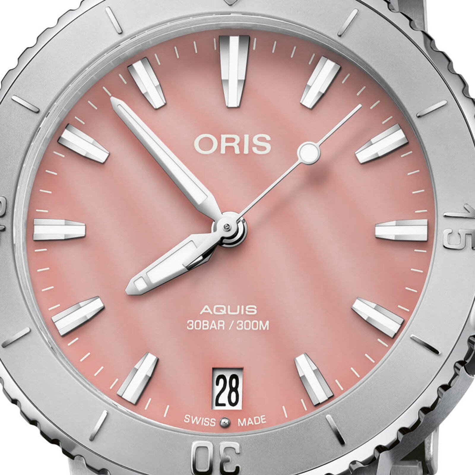 Close-up of the Oris Aquis Date watch, showcasing a blush pink dial with silver markers and hands, date display at 6 o’clock, and “Swiss Made” text.