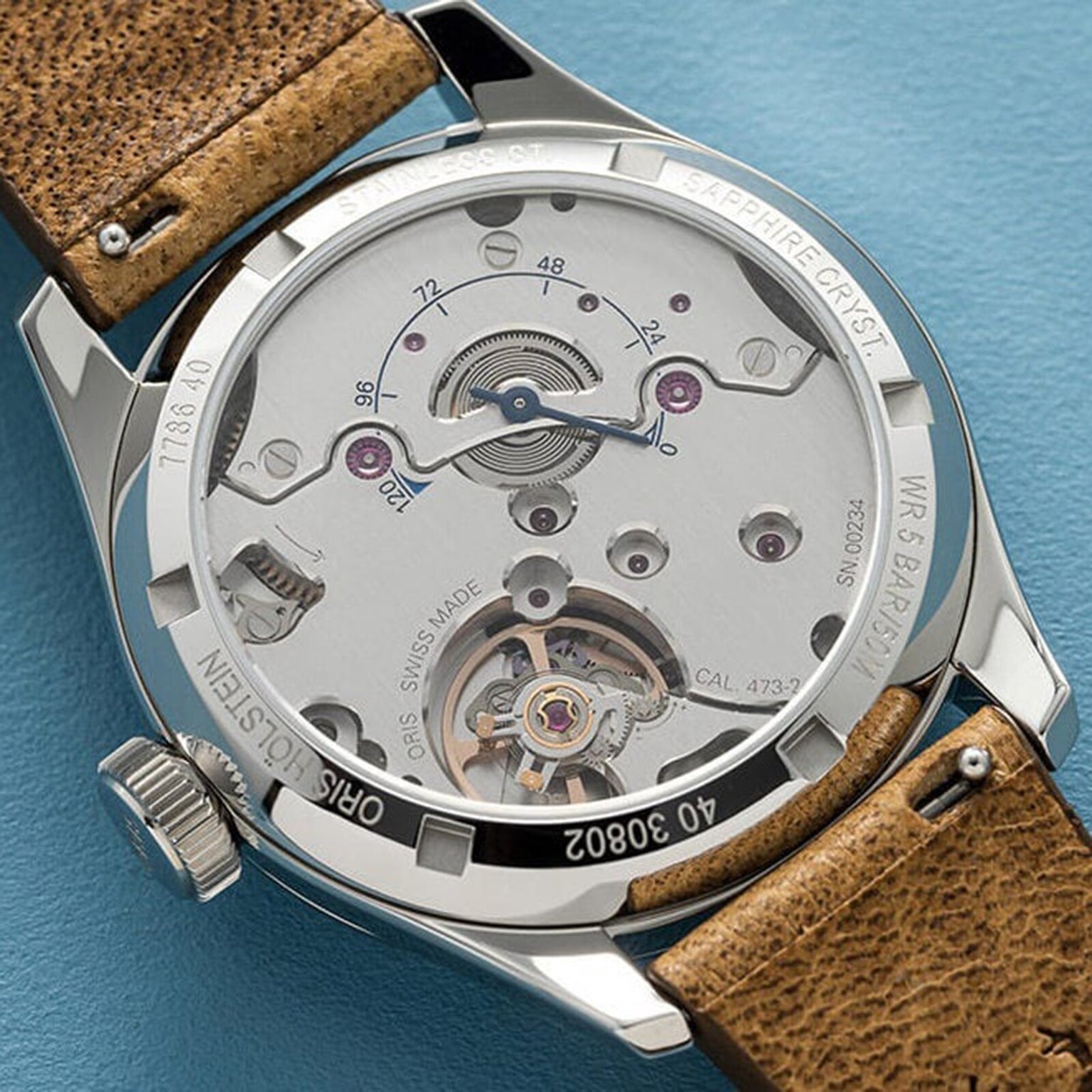 Close-up of the Oris Big Crown Pointer Date Calibre 473’s open case back, showcasing its hand-wound movement and intricate mechanics, complemented by a brown leather strap.