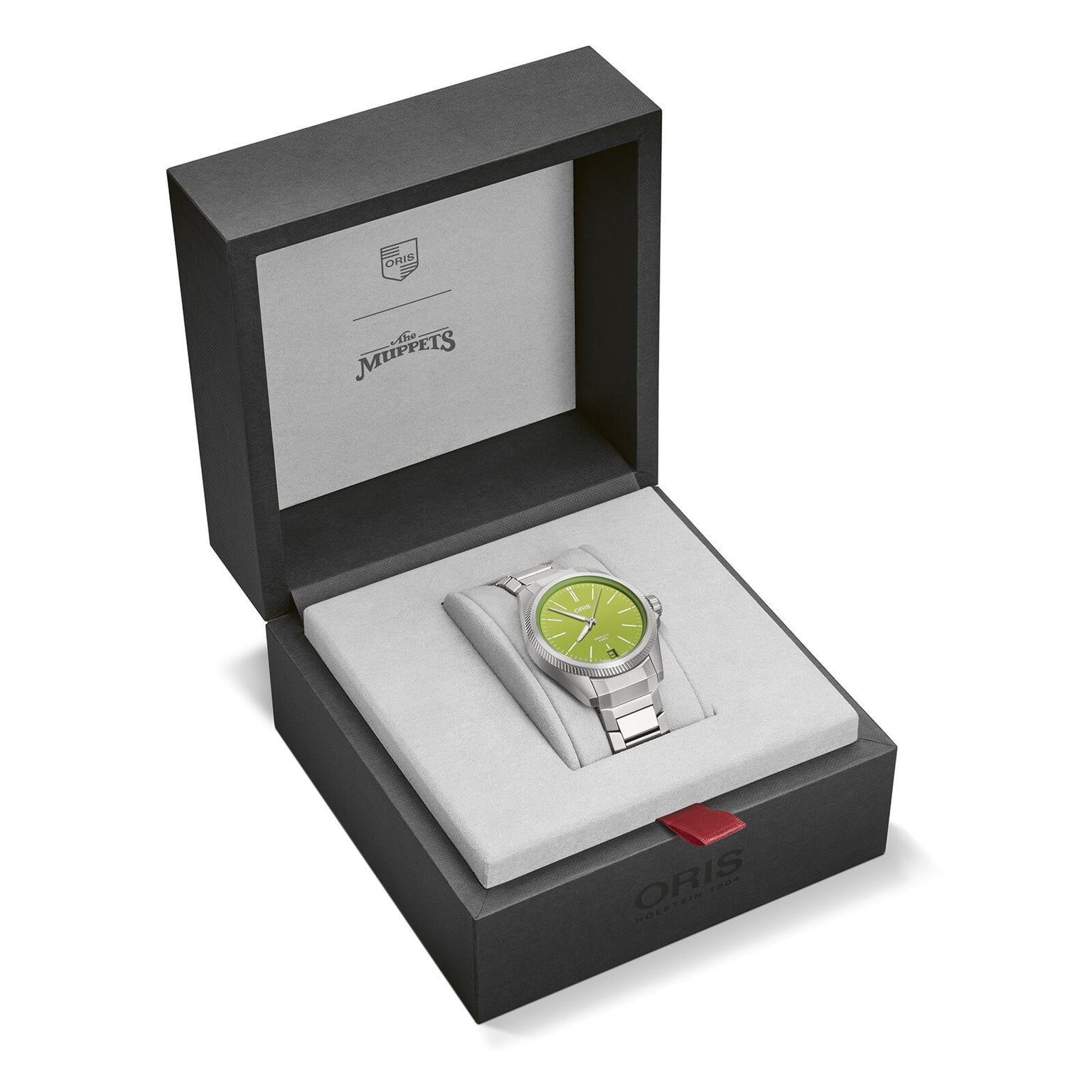 The Oris ProPilot X Kermit Edition, a silver wristwatch with a green face, is shown in an open black and gray Oris watch box featuring The Muppets branding inside the lid.