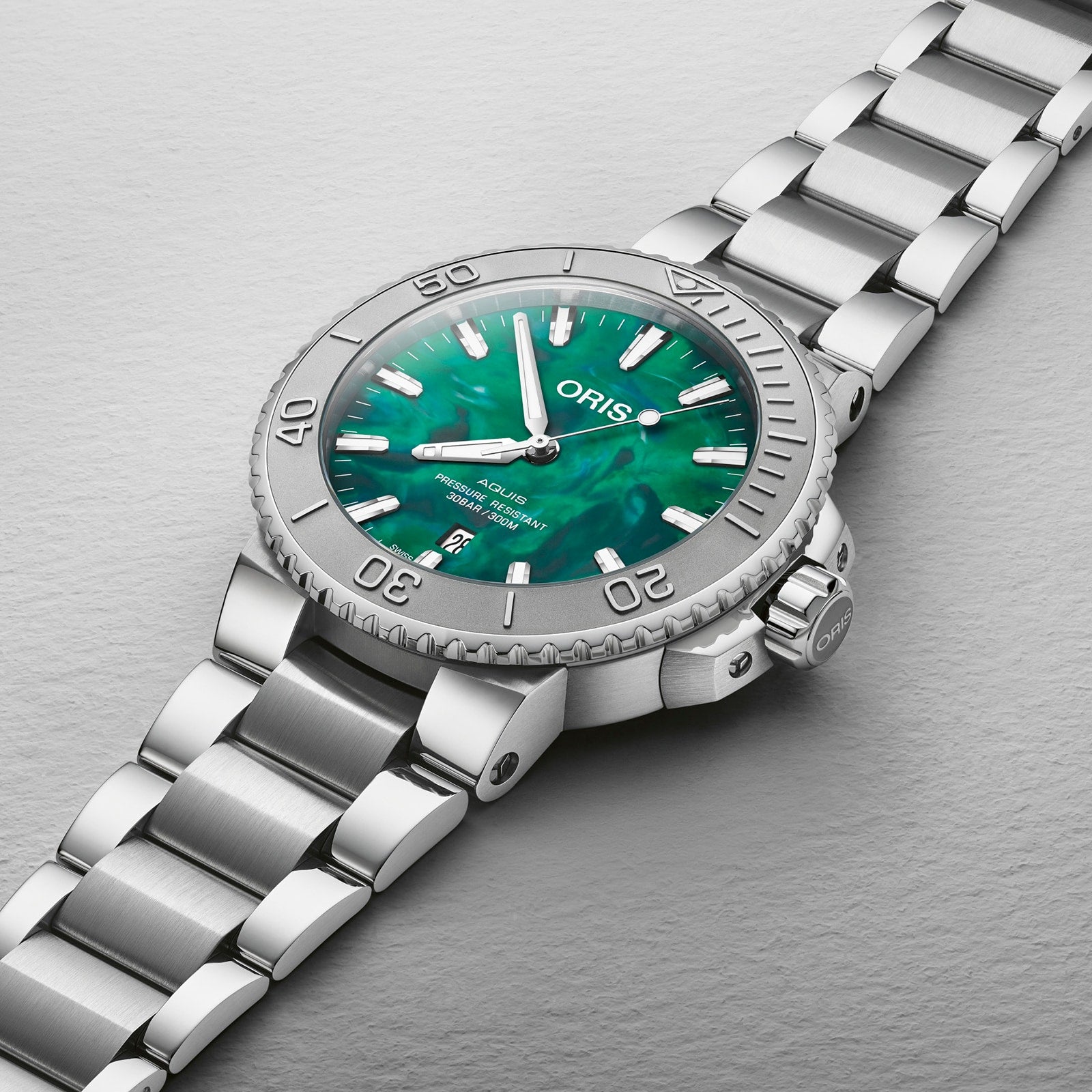 The Oris Aquis Oris X Bracenet is a silver wristwatch with a green mother-of-pearl dial and a matching silver metal bracelet.