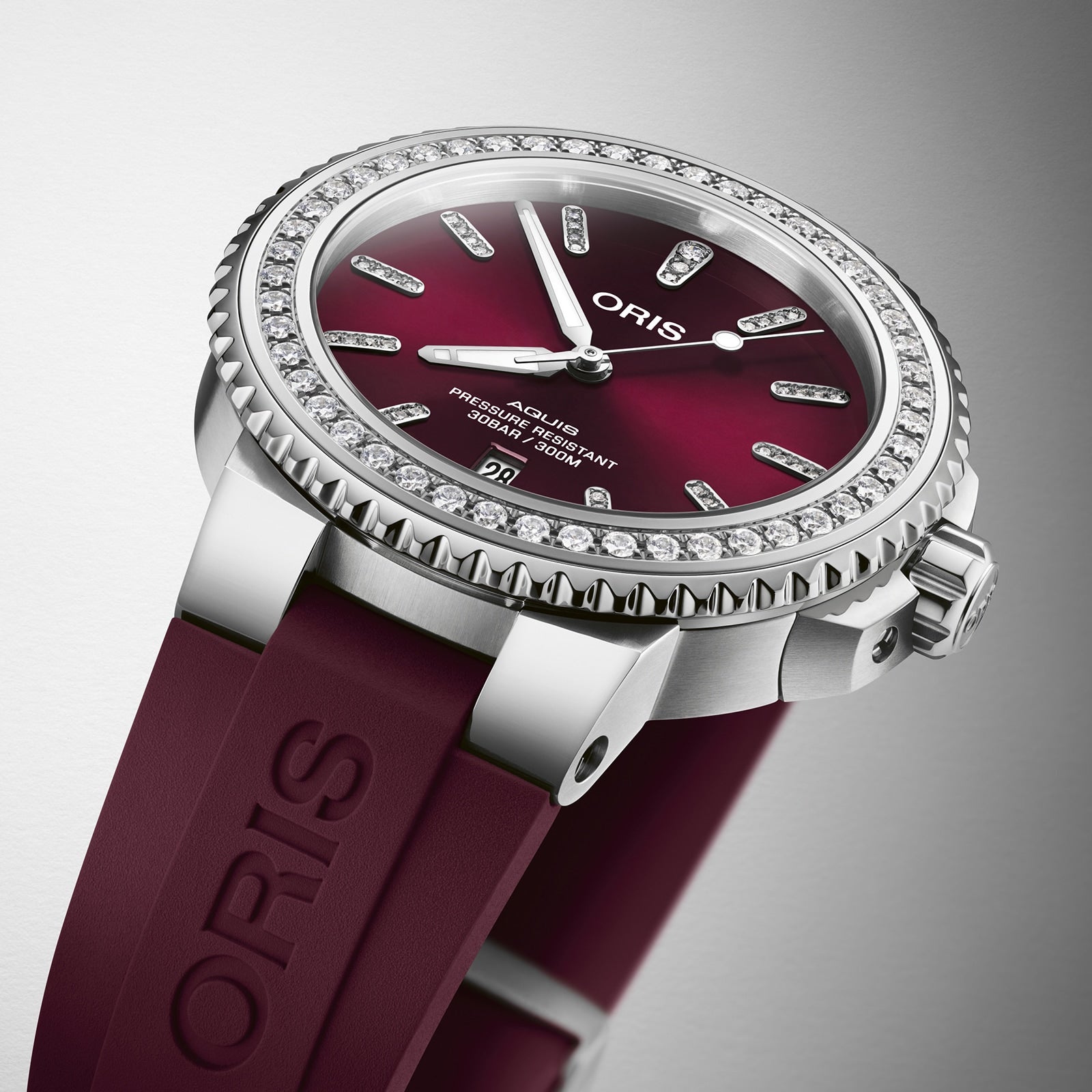 Close-up of the Oris Aquis Date Diamonds watch featuring a burgundy dial, diamond bezel, and a matching burgundy rubber strap.