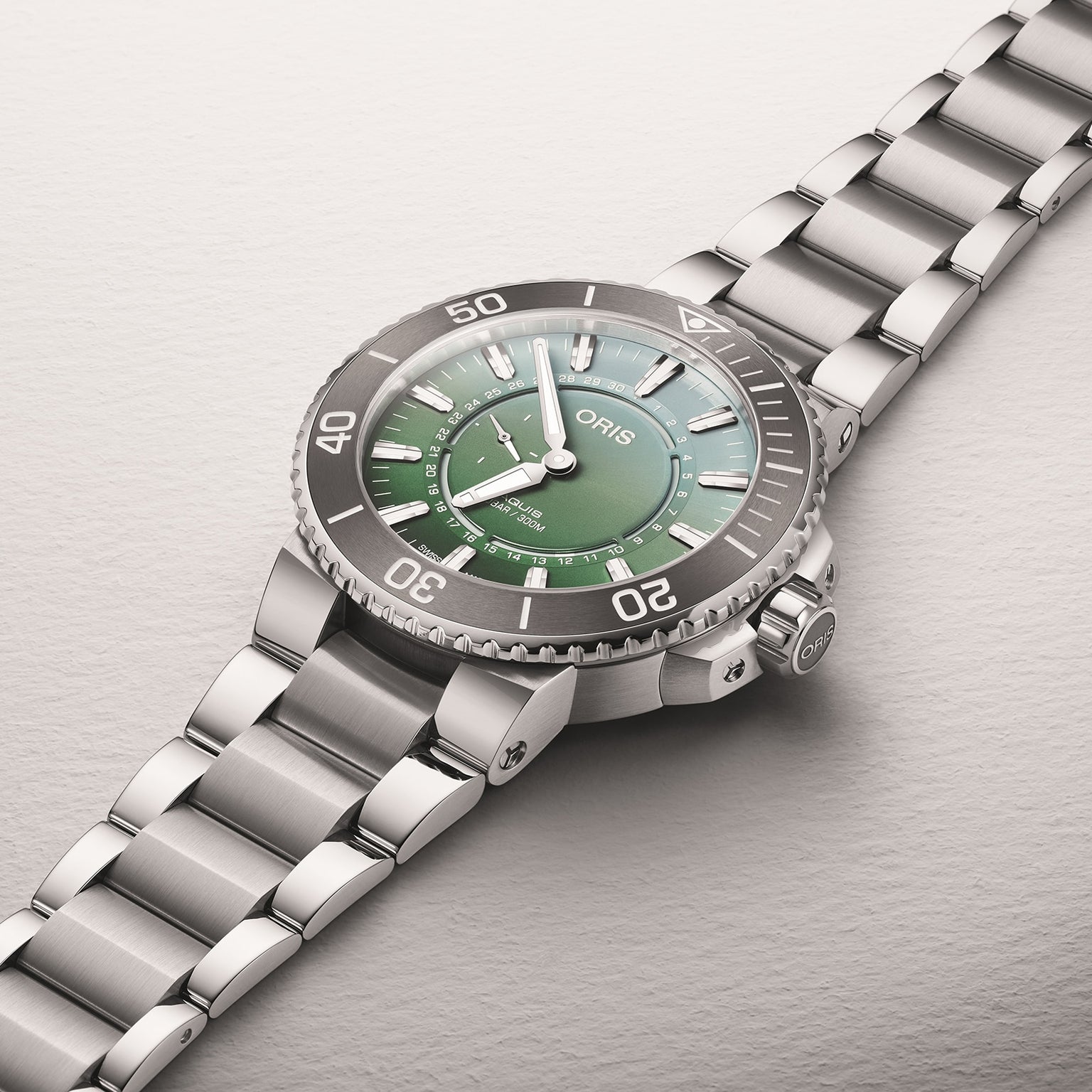 The Oris Dat Watt Limited Edition II is a stainless steel watch with a green dial, silver hour markers, and a metal link bracelet, inspired by Wadden Sea conservation, shown against a light background.