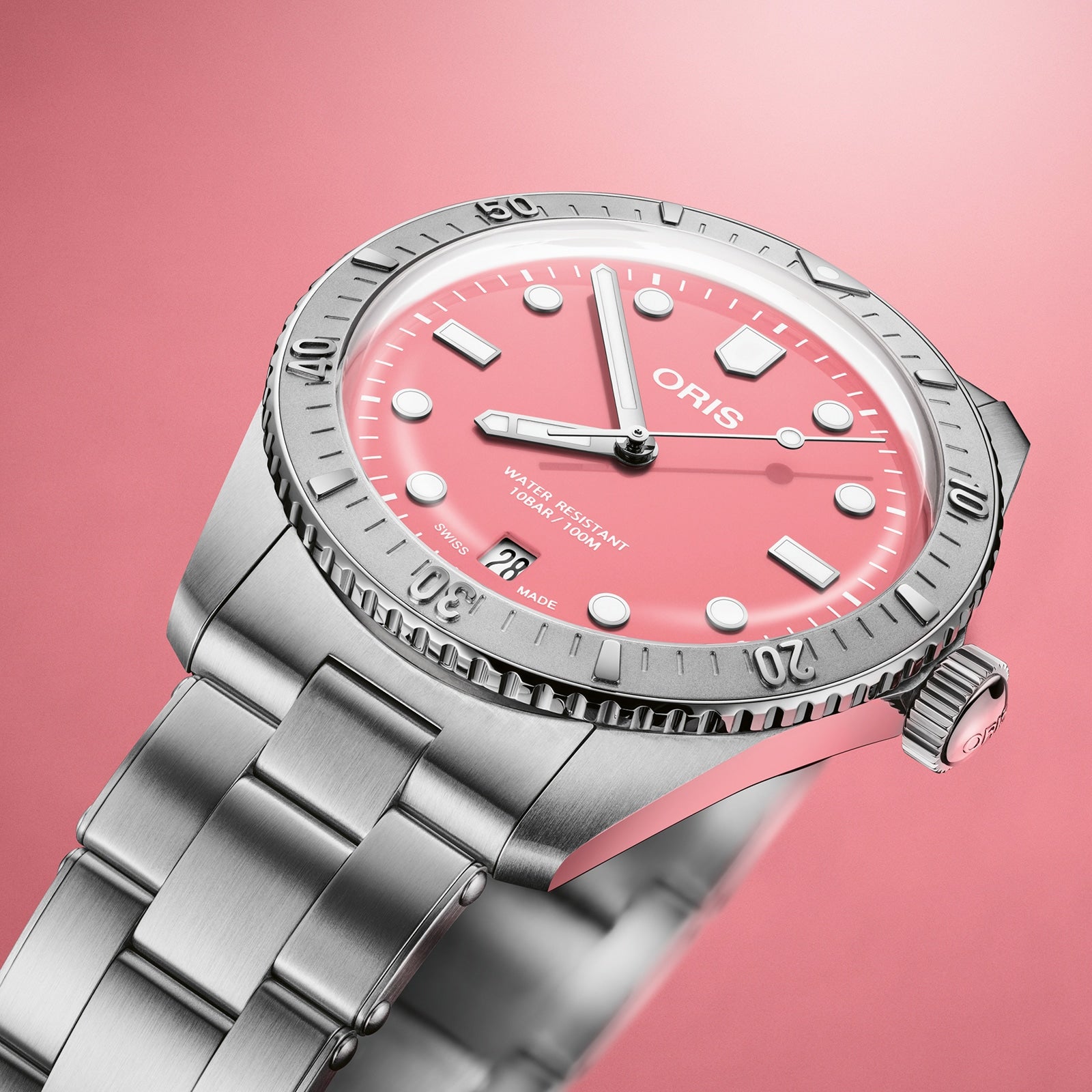 The Oris Divers Sixty‑Five Cotton Candy wristwatch features a pink dial and silver bezel, showcased against a matching pink background.