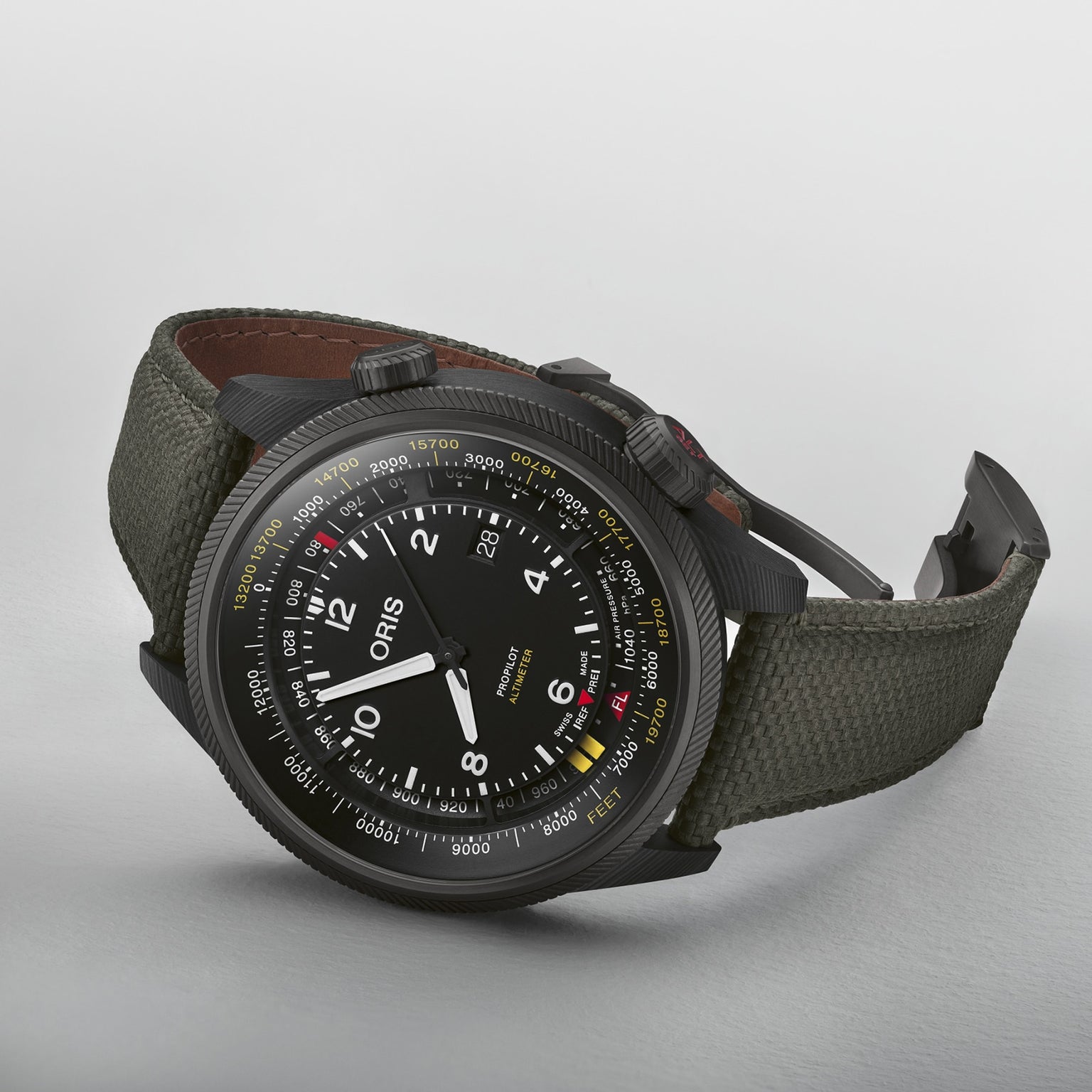 An Oris ProPilot Altimeter wristwatch featuring a black case, fabric strap, white numerals, multi-scale dial, and dual crowns with integrated altimeter module, displayed on a white surface.